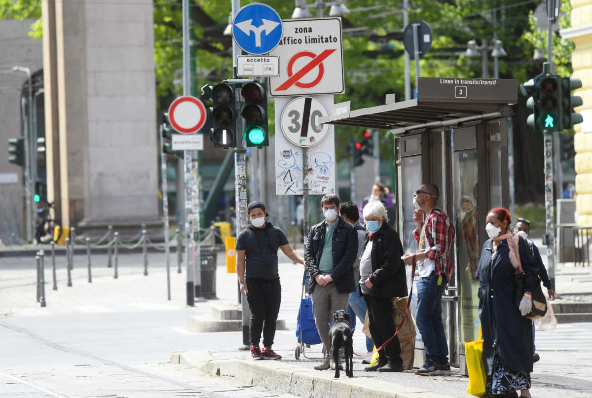 People wearing protective masks wait at a bus stop in an increasingly busy street, amid the coronavirus disease (COVID-19) outbreak, in Milan, Italy April 18, 2020. REUTERS