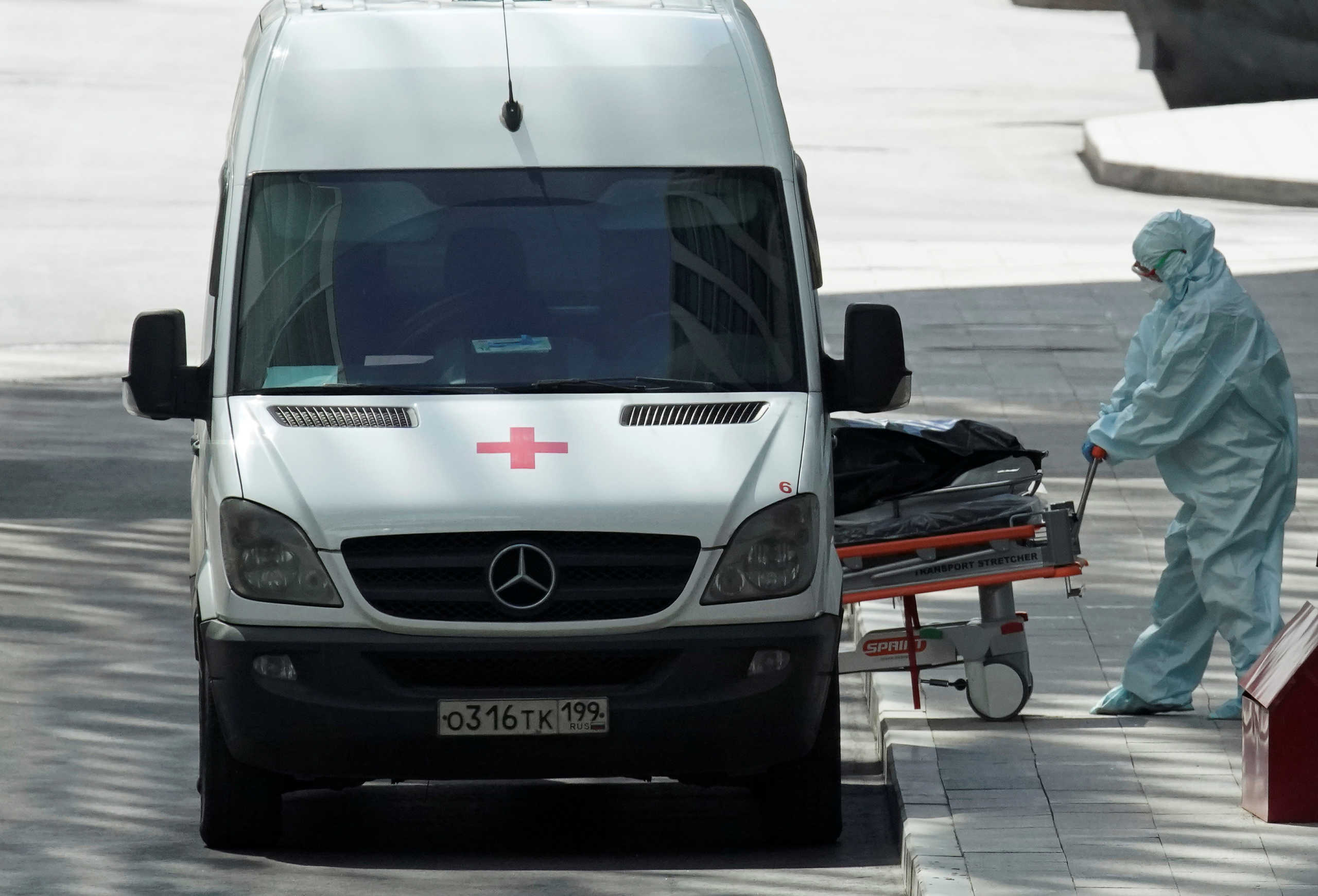 A medical specialist wearing protective gear pushes a stretcher next to an ambulance while relocating a non-transparent bag, which presumably contains a human body, outside a hospital for patients infected with the coronavirus disease (COVID-19) on the outskirts of Moscow, Russia April 21, 2020. REUTERS