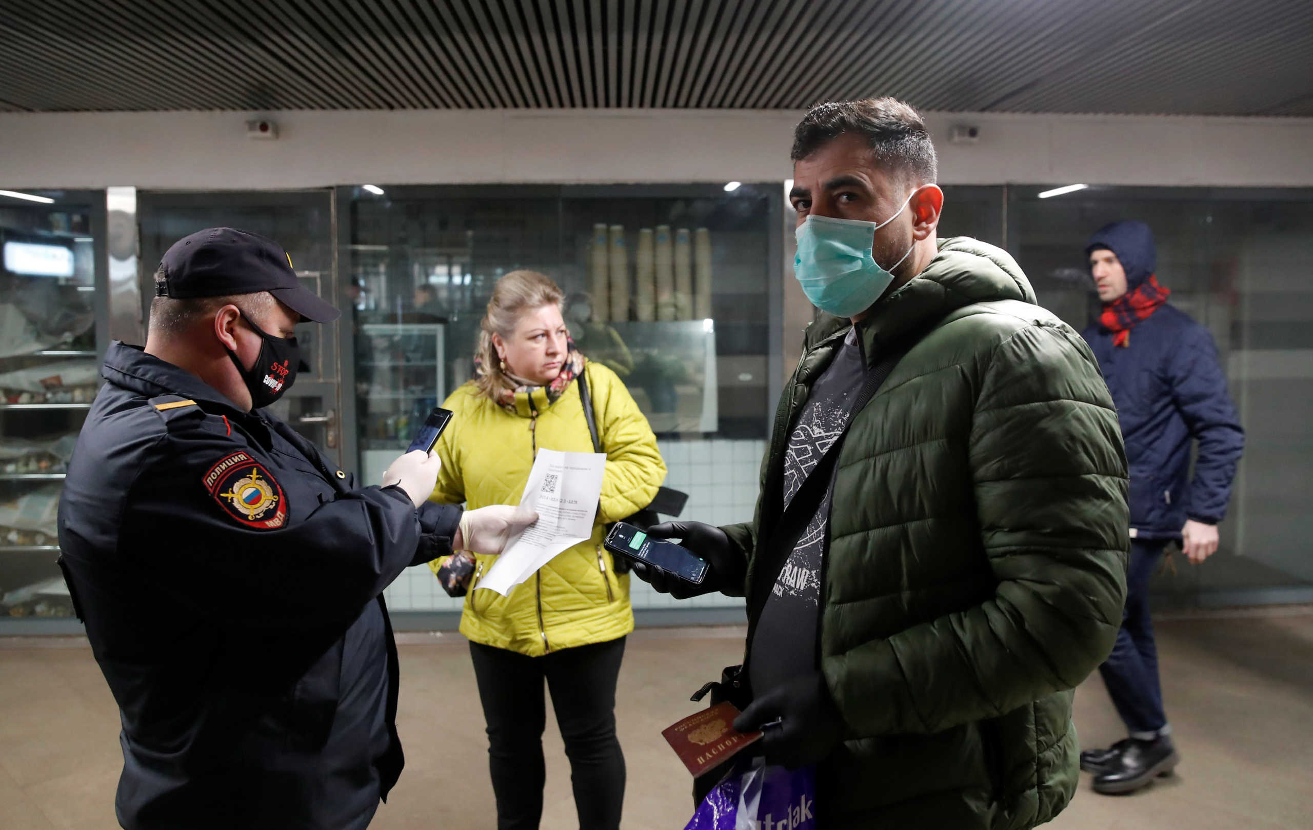 A police officer verifies pedestrians' documents near an entrance to a metro station in Moscow, Russia April 15, 2020. Moscow authorities ordered a partial lockdown and introduced digital permits to control movement around the city amid the coronavirus disease (COVID-19) outbreak. REUTERS