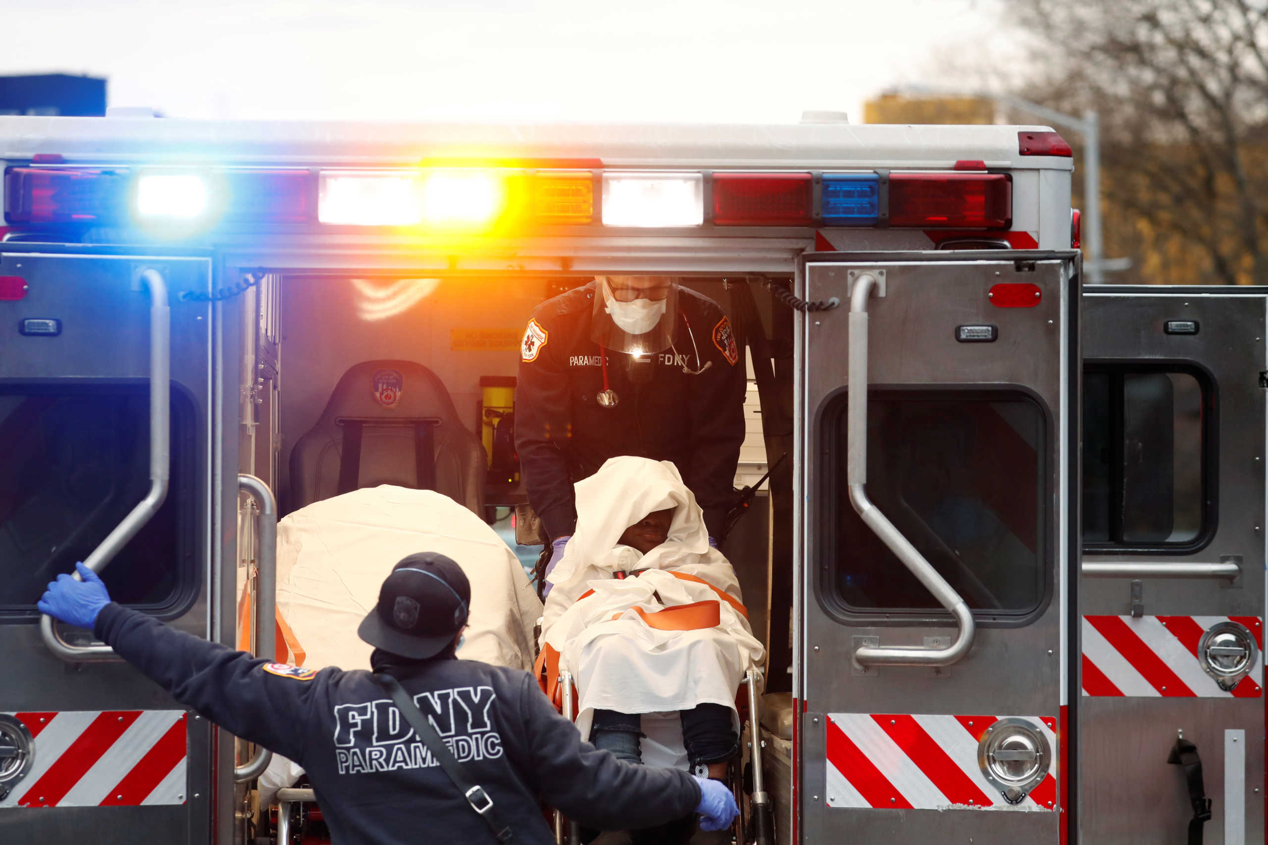 Emergency medical technicians wear personal protective equipment as they help a patient who had suffered a cardiac arrest in front of the Howard Houses as the outbreak of the coronavirus disease (COVID19) continues in the Brooklyn borough of New York, U.S., April 14, 2020. REUTERS