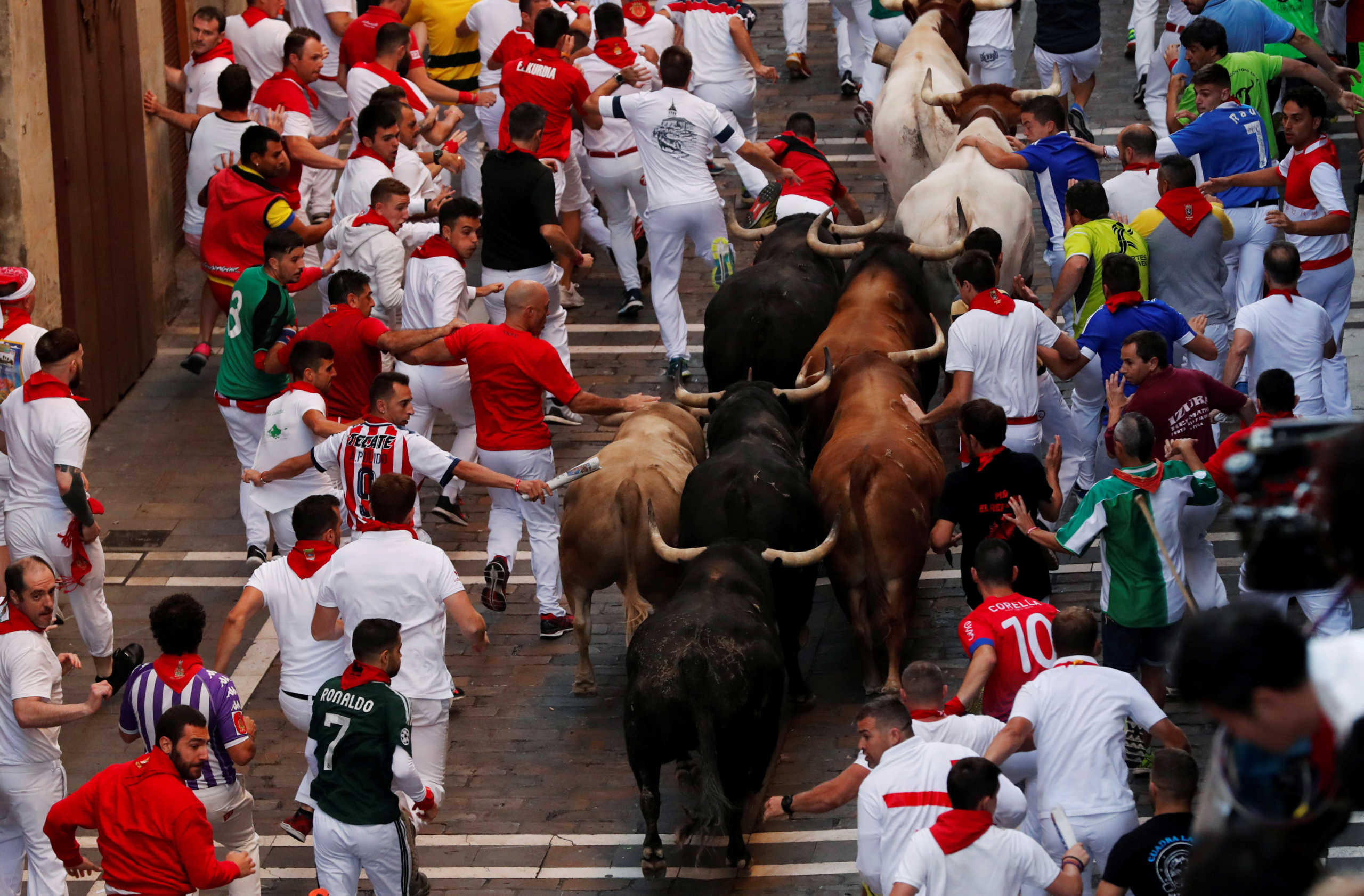 FILE PHOTO: Revellers sprint near bulls and steers during the running of the bulls at the San Fermin festival in Pamplona, Spain, July 12, 2019. REUTERS