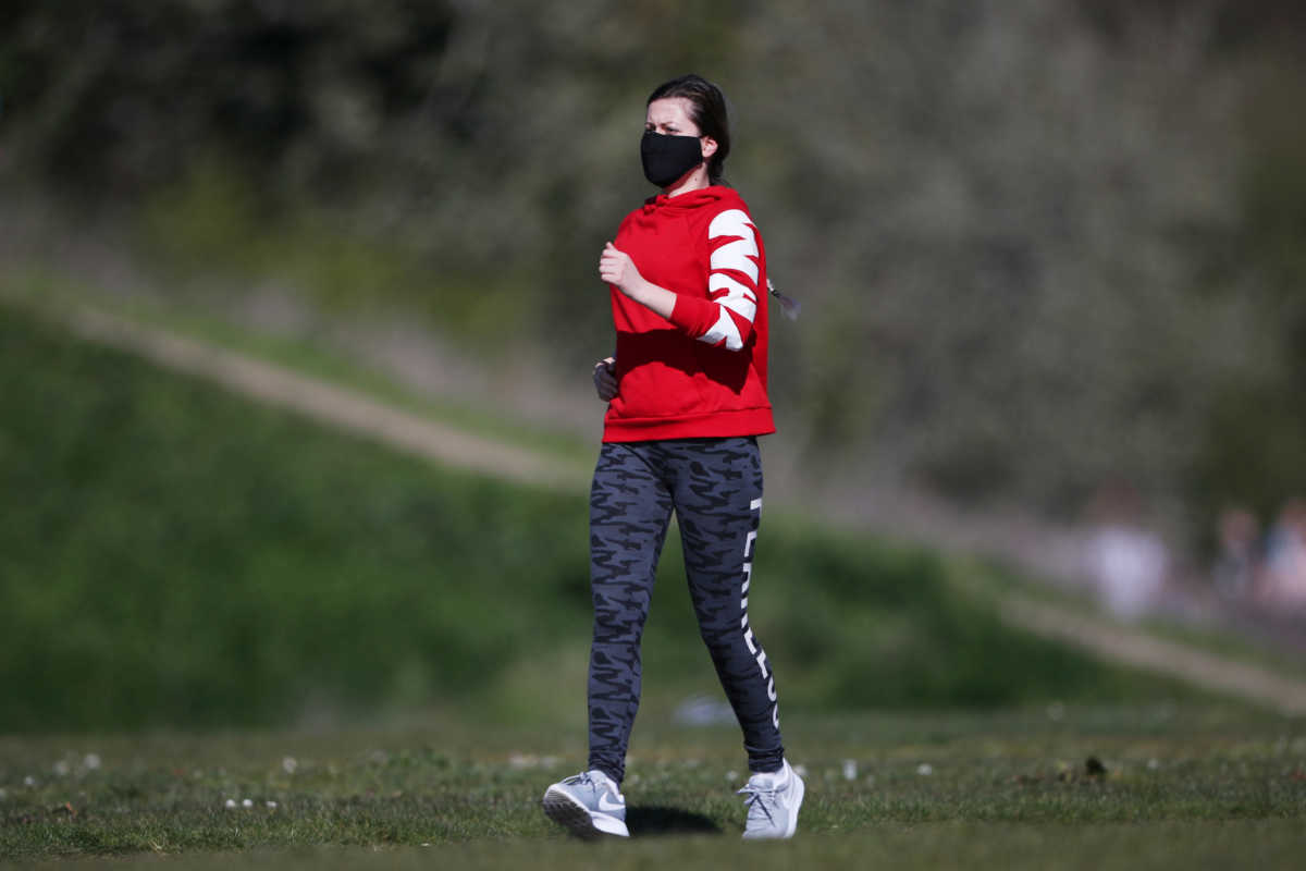A woman wearing a protective mask jogs in Burgess Park, as the spread of the coronavirus disease (COVID-19) continues, London, Britain, April 5, 2020. REUTERS