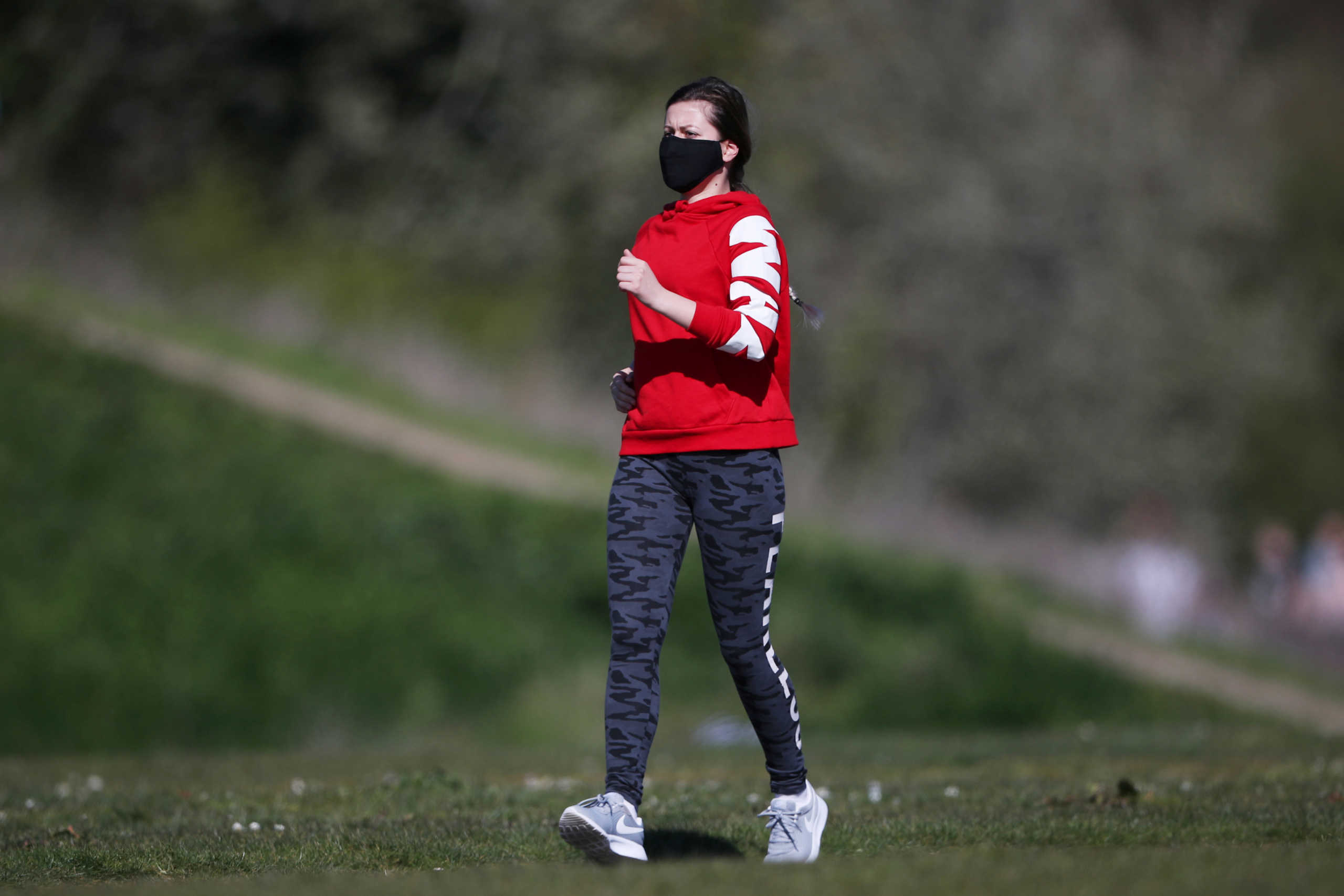 A woman wearing a protective mask jogs in Burgess Park, as the spread of the coronavirus disease (COVID-19) continues, London, Britain, April 5, 2020. REUTERS