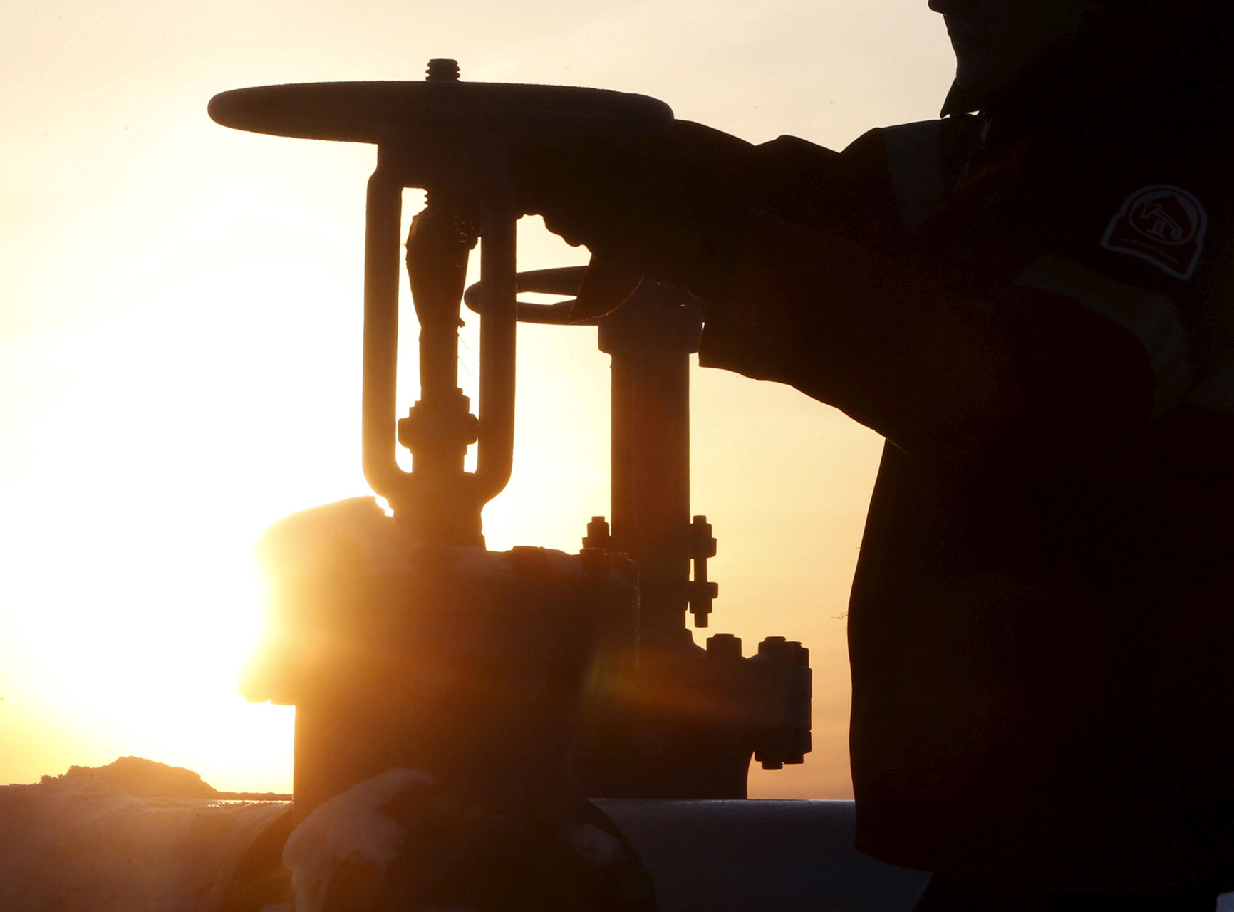 FILE PHOTO: A worker checks the valve of an oil pipe at the Lukoil company owned Imilorskoye oil field outside the West Siberian city of Kogalym, Russia, January 25, 2016.  REUTERS