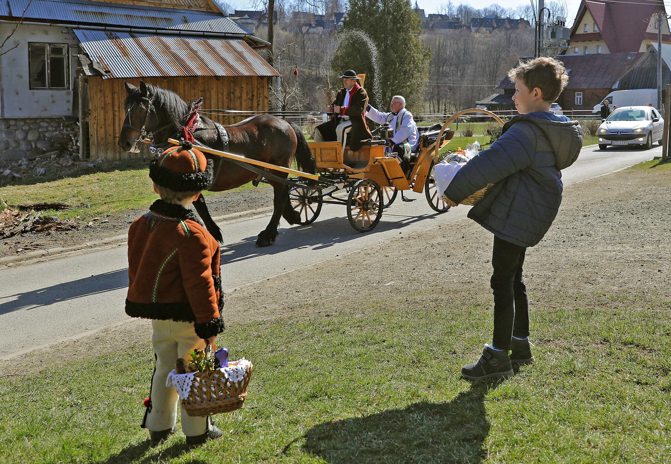 A priest sprinkles holy water on believers and their food while circuiting all over the vicinity in a horse-drawn cart during the celebrations of Holy Saturday on the eve of Easter amid the coronavirus (COVID-19) pandemic in Zakopane, Poland April 11, 2020. Marek Podmokly