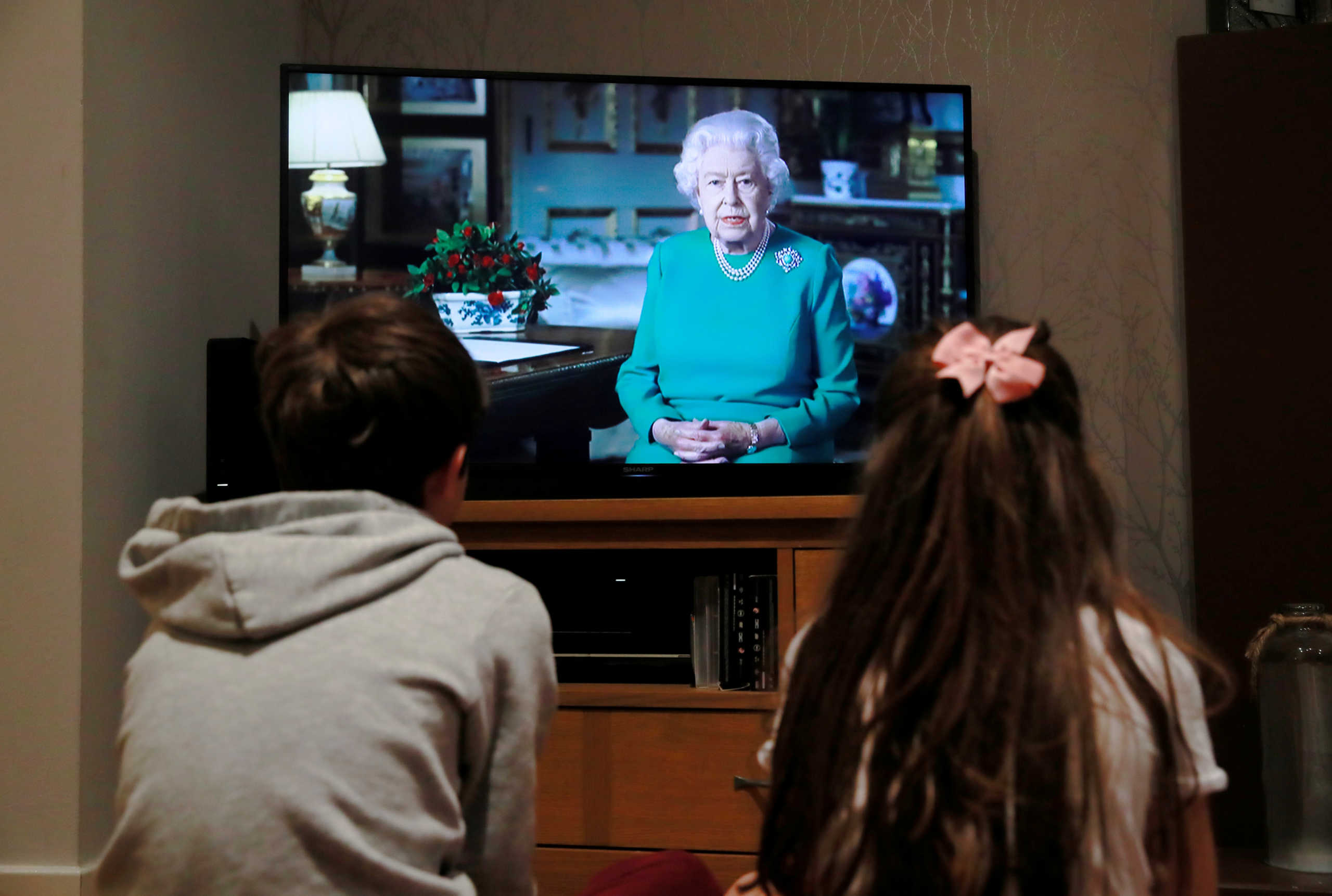 Noah (9) and Milly (7) watch Britain's Queen Elizabeth II during a televised address to the nation at their home, as the spread of the coronavirus disease (COVID-19) continues, Hertford, Britain, April 5, 2020. REUTERS