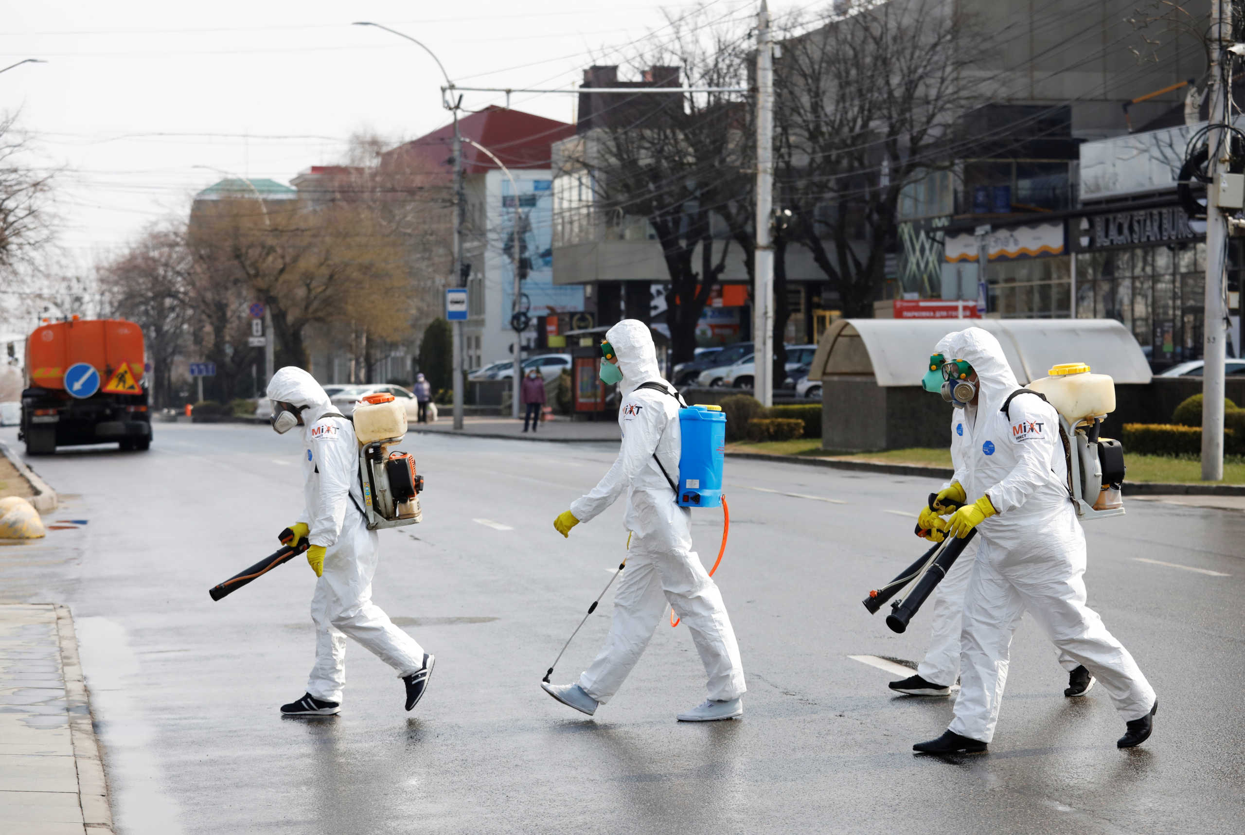 Specialists wearing protective gear cross the road while they sanitize public facilities to prevent the spread of coronavirus disease (COVID-19) in Stavropol, Russia April 1, 2020. REUTERS