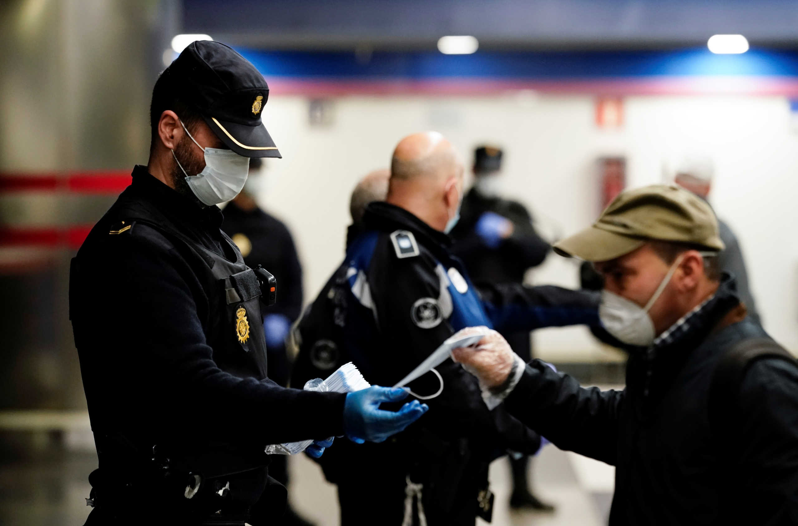 A police officer gives out free protective face masks at a metro station during the lockdown amid the coronavirus disease (COVID-19) outbreak in Madrid, Spain, April 13, 2020. REUTERS