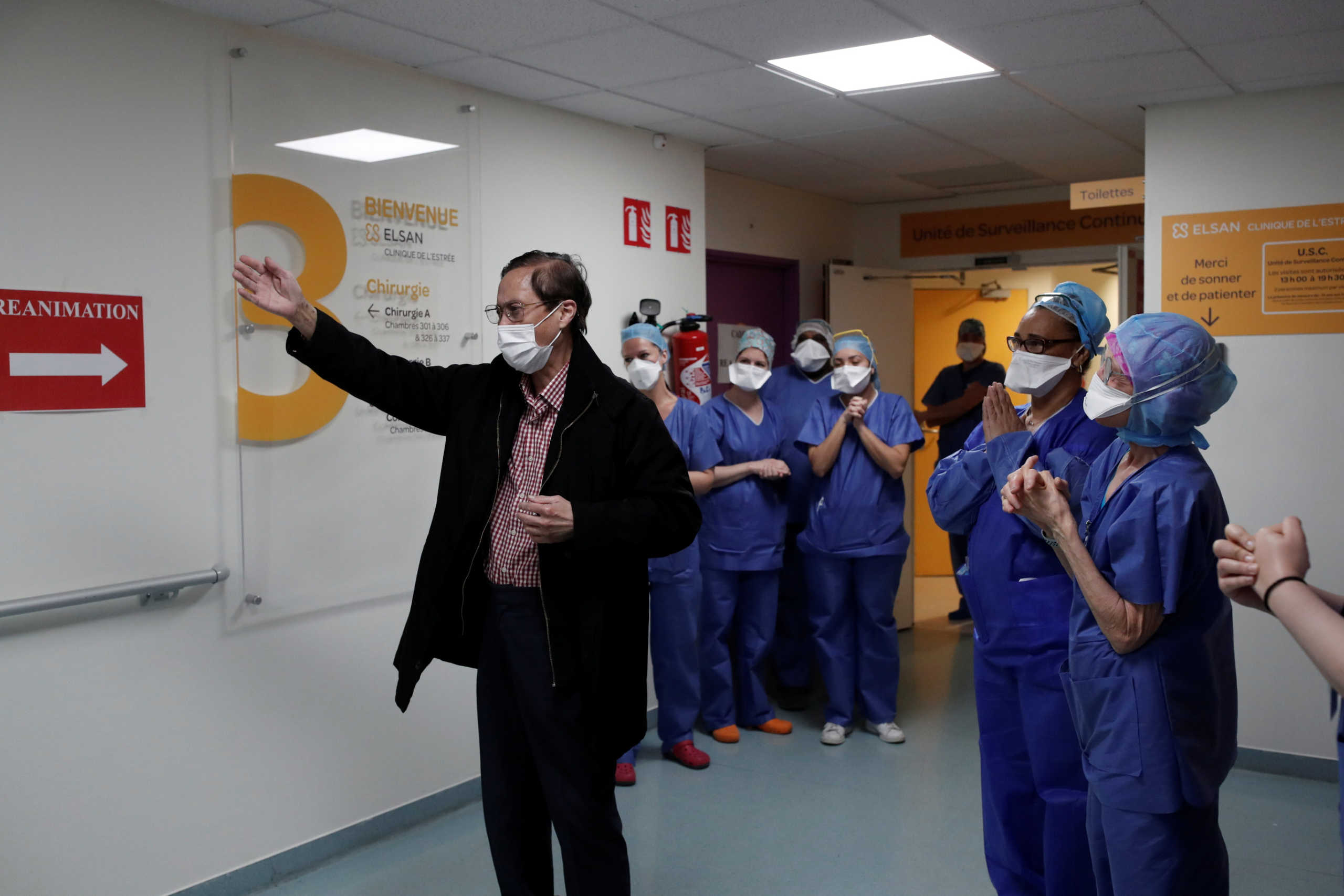 Medical staff members applaud patient Mang Phother, 61, who spent 16 days in the Intensive Care Unit (ICU) for coronavirus disease (COVID-19), as he leaves the Clinique de l'Estree private hospital in Stains near Paris as the spread of the coronavirus disease continues in France, April 23, 2020.   REUTERS