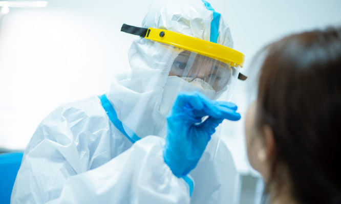 Coronavirus test - Medical worker taking a swab for corona virus sample from potentially infected woman with the isolation gown or protective suits and surgical face masks