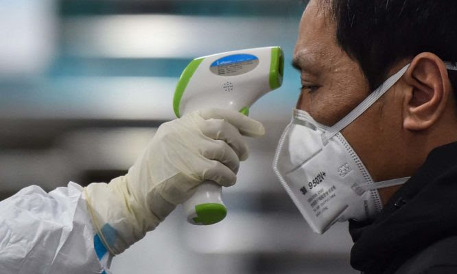 A medical staff member takes the temperature of a man at the Wuhan Red Cross Hospital in China on Jan. 25. HECTOR RETAMAL