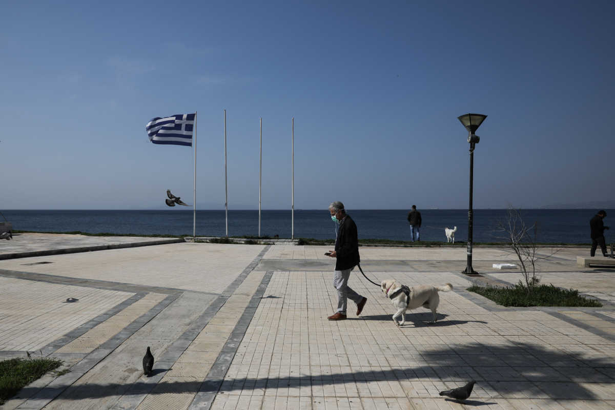 A man wearing a protective face mask walks his dog on a seaside promenade, following the outbreak of coronavirus disease (COVID-19), in Athens, Greece, March 31, 2020. REUTERS