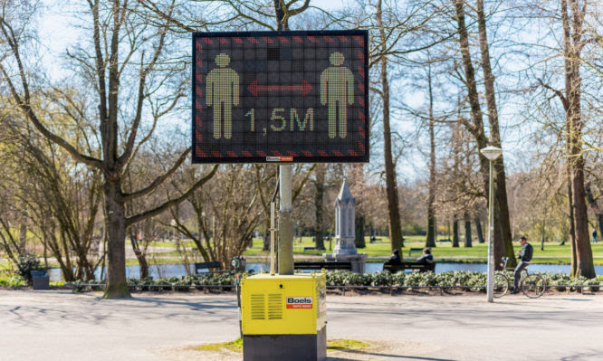 Amsterdam, Netherlands - March 22, 2020: Keep Distance of 1.5 meter Warning Sign on Digital Display in a public park, reminding people of social distancing in order to avoid the coronavirus spread.