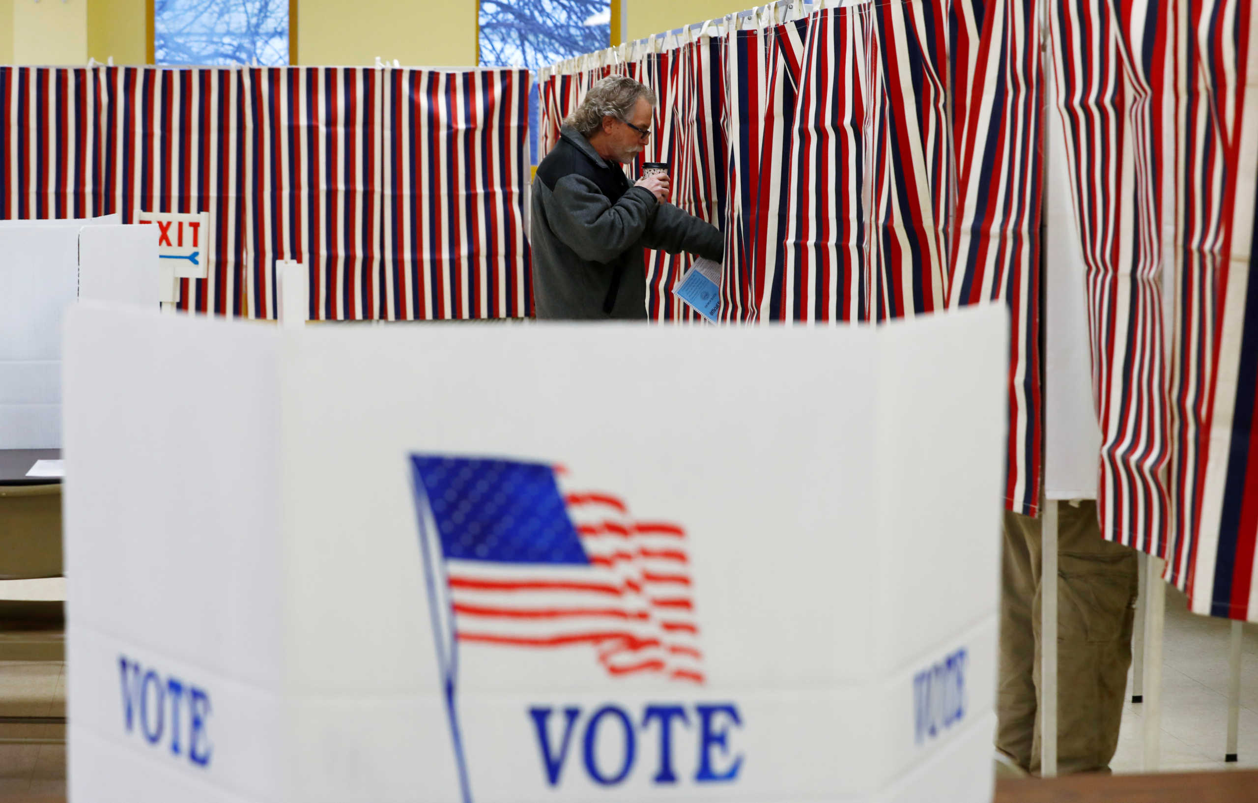 FILE PHOTO: A voter takes his coffee with him as he enters the voting booth to mark his ballot with his vote in New Hampshire's first-in-the-nation U.S. presidential primary election in Allenstown, New Hampshire, U.S. February 11, 2020. REUTERS