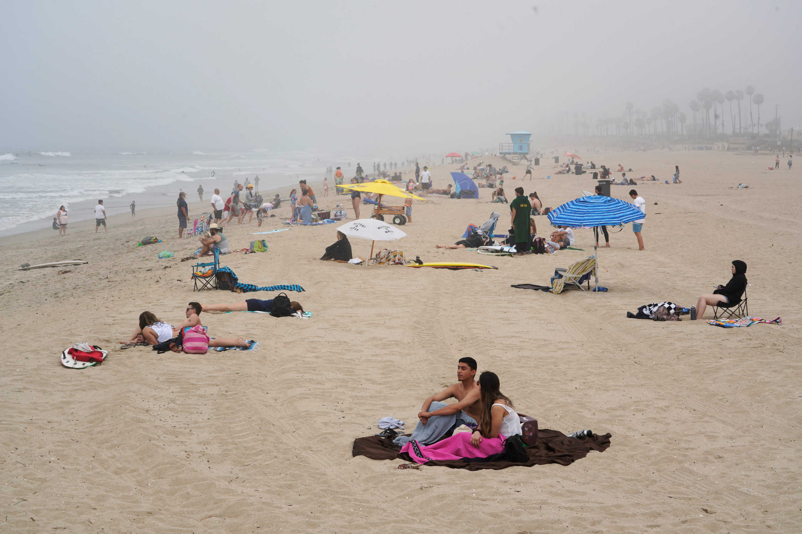 People sit in groups at Huntington City Beach during the outbreak of the coronavirus disease (COVID-19) in Huntington Beach, California, U.S., April 25, 2020. REUTERS