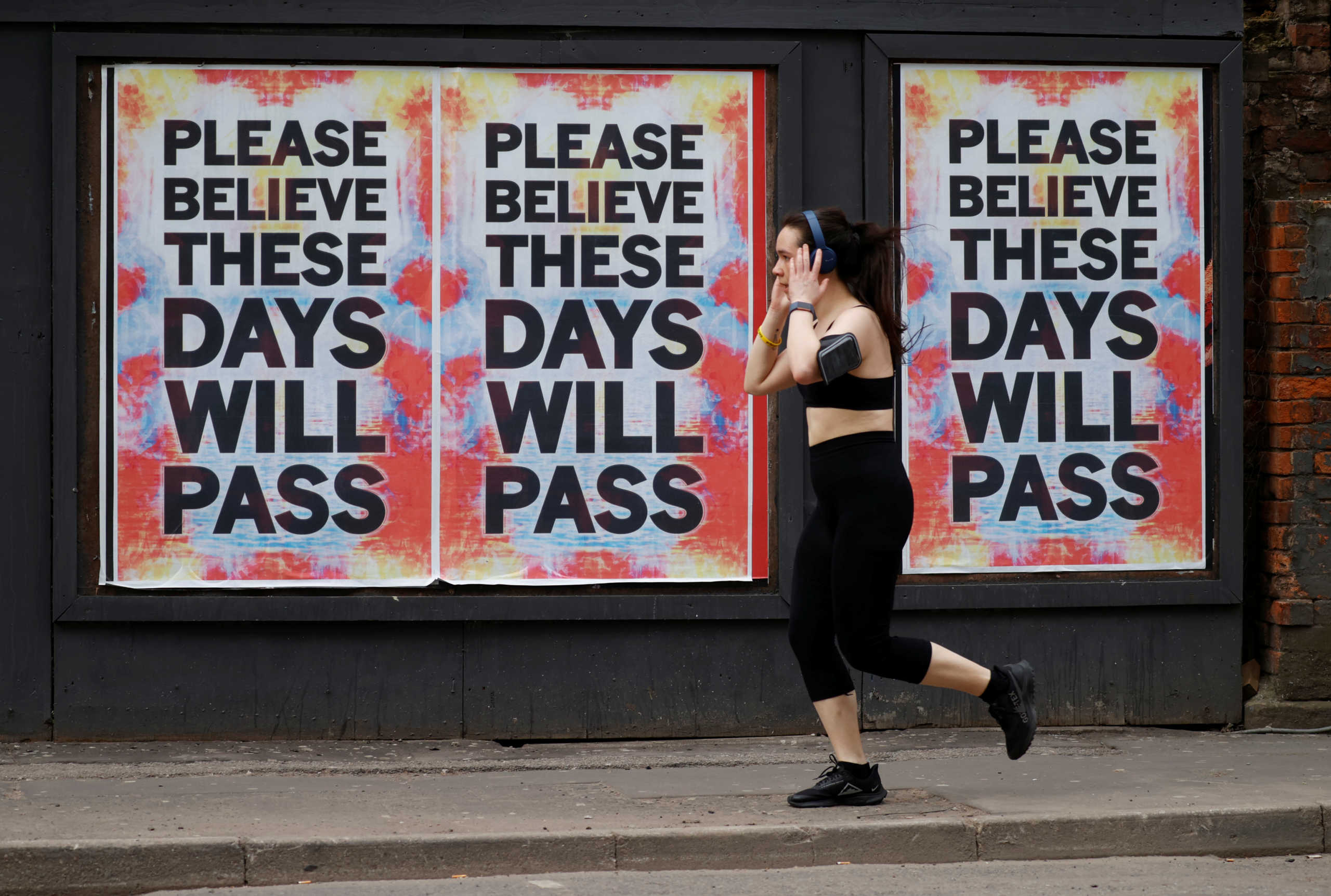 A person runs past posters with messages in Manchester, as the spread of the coronavirus disease (COVID-19) continues, Manchester, Britain, April 12, 2020. REUTERS
