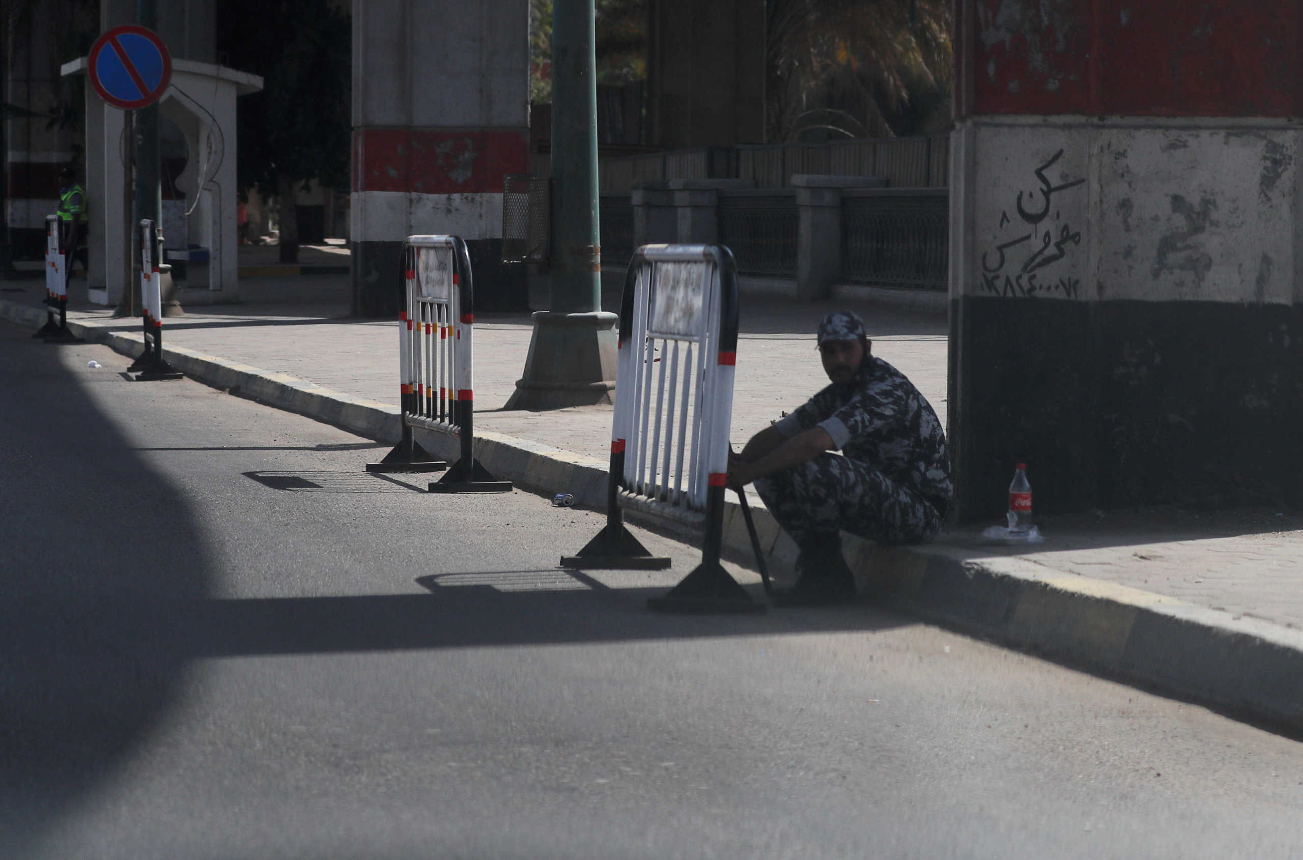 An Egyptian police officer sits next to a wall painted with colors of the Egypt's flag and next to barricades placed to ensure people abide by restrictions during the national holiday of Sham el-Nessim marking the beginning of spring season, with almost empty streets to contain the spread of the coronavirus disease (COVID-19), on Nile Corniche, in Cairo, Egypt April 20, 2020. REUTERS