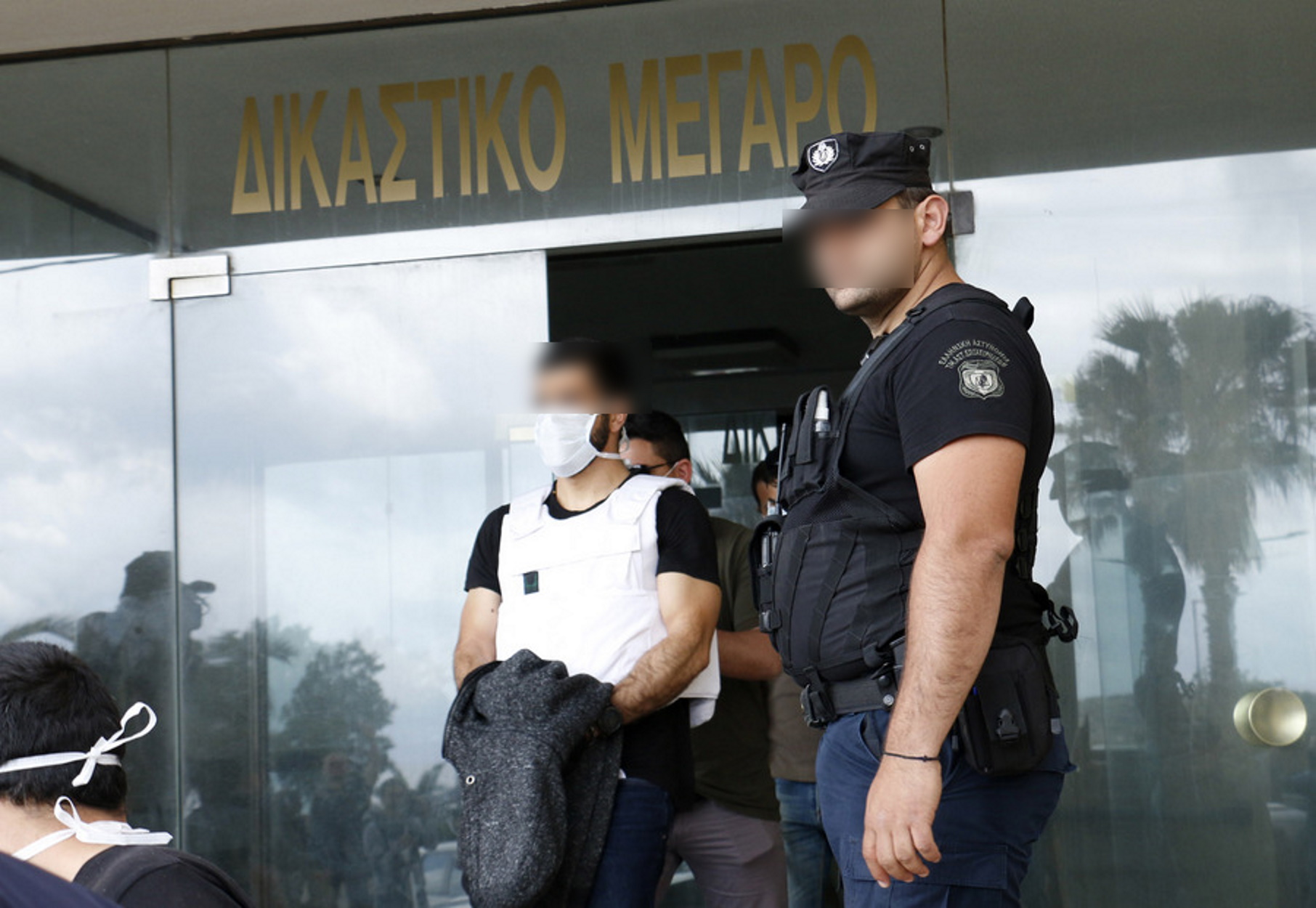 ΣΗΜΕΙΩΣΗ ΓΙΑ ΤΟΥΣ EDITORS. ΠΡΟΣΟΧΗ: Η φωτογραφία έχει ληφθεί χωρίς τη ρητή άδεια των εικονιζόμενων. Η δημοσίευση των χαρακτηριστικών τους γίνεται αποκλειστικά με ευθύνη του συνδρομητή. Αστυνομικοί μεταφέρουν τον  29χρονο φερόμενο δράστη και γιο του 63χρονου Λευτέρη Καλομοίρη που έπεσε νεκρός στο διπλό φονικό στα Ανώγεια, μετά την κατάθεσή του στον Εισαγγελέα, τη Δευτέρα 4 Μαΐου 2020, στο Δικαστικό Μέγαρο Ρεθύμνου. Ο 29χρονος που φορούσε αλεξίσφαιρο γιλέκο αποχώρησε από το Δικαστικό Μέγαρο, όπου βρίσκονταν σε επιφυλακή αστυνομικές δυνάμεις. Ο 29χρονος, φέρεται να πυροβόλησε τον 30χρονο, ο οποίος νωρίτερα είχε σκοτώσει τον 63χρονο πατέρα του. Οι δύο νέοι διαπληκτίστηκαν, ο 30χρονος αποχώρησε από το σημείο της έντασης, αλλά επέστρεψε αργότερα οπλισμένος. Ο 63χρονος μπροστά στο όπλο ζήτησε από τον 30χρονο να φύγει και να δώσει τέλος στην ένταση, όμως ο 30χρονος τον πυροβόλησε με αποτέλεσμα τον θανάσιμο τραυματισμό του πρώτου. Ο γιος του θύματος πυροβόλησε στη συνέχεια τον 30χρονο και τράπηκε σε φυγή.  Δύο νεκροί και ένας ελαφρά τραυματίας είναι το τραγικό αποτέλεσμα μιας έντονης λογομαχίας στα Ανώγεια Ρεθύμνου, με ένα ολόκληρο χωριό να βρίσκεται σε αναστάτωση και οι κάτοικοι της Κρήτης να αναρωτιούνται για το πως οδηγήθηκαν στον θάνατο οι δύο άνδρες, ηλικίας 63 και 30 ετών.  ΑΠΕ-ΜΠΕ