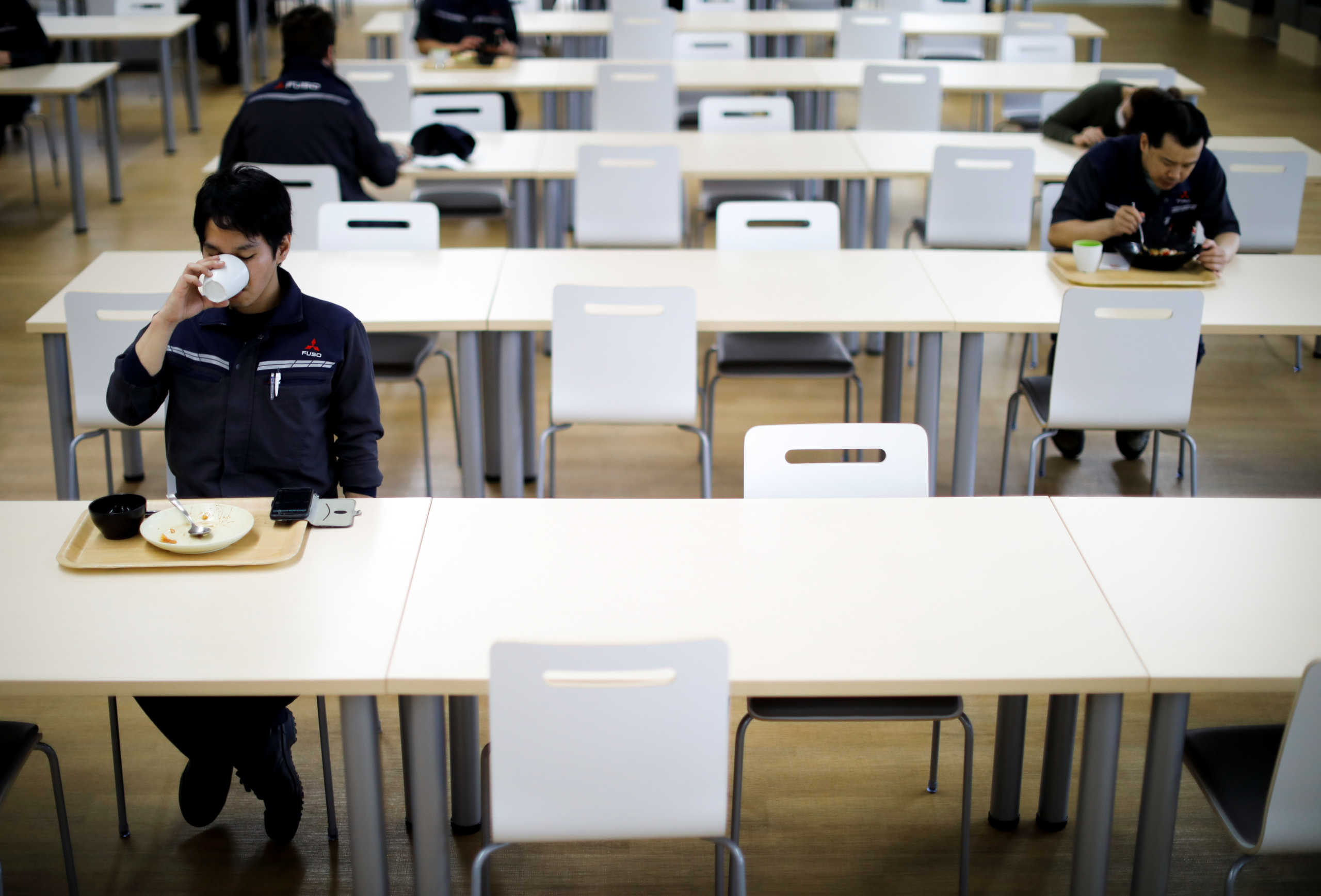 Employees observe social distancing during their lunch break at the staff canteen as the automaker ramps up car production with new security and health measures as a step to resume full operations, during the outbreak of the coronavirus disease (COVID-19), at Kawasaki factory of Mitsubishi Fuso Truck and Bus Corp., owned by Germany-based Daimler AG, in Kawasaki, south of Tokyo, Japan May 18, 2020.  REUTERS