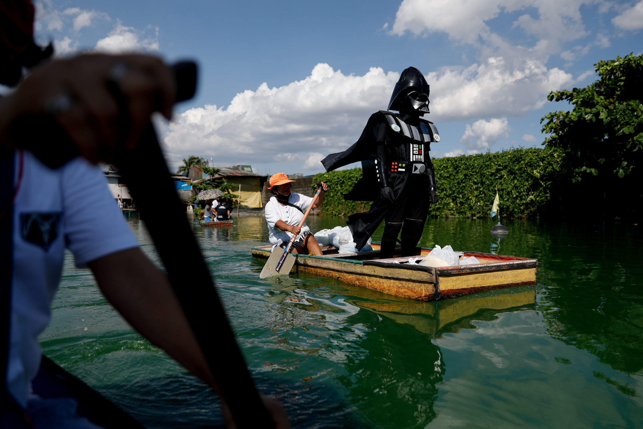 A village officer dressed as the Star Wars character Darth Vader rides a small boat to deliver relief goods to residents in the flooded Artex Compound in Malabon, Metro Manila, Philippines, May 4, 2020. REUTERS