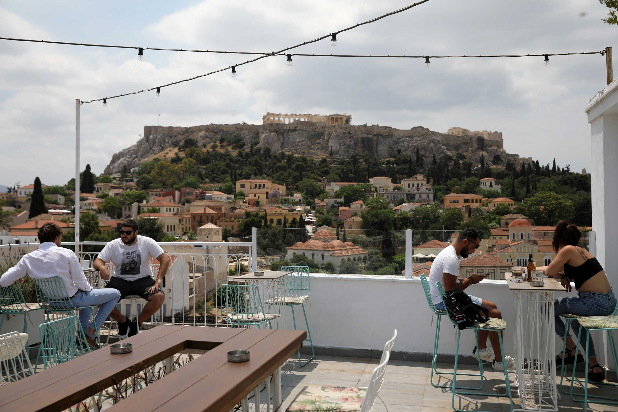 Customers sit in a coffee shop, with the Acropolis hill in the background, as restaurants reopen following the easing of measures against the spread of the coronavirus disease (COVID-19), in Athens, Greece May 25, 2020. REUTERS