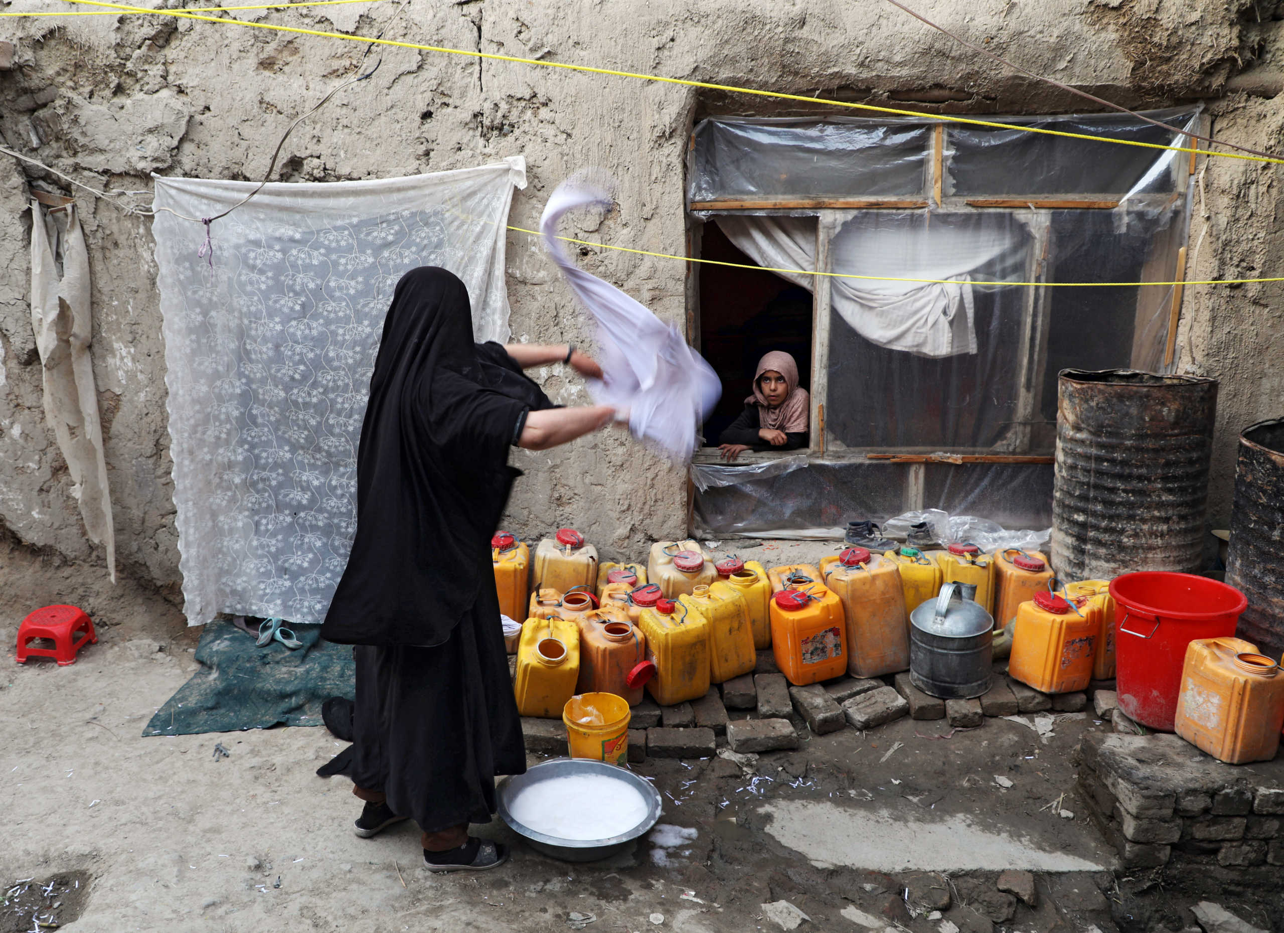 Delkhah Sultani, 30, an Afghan widow who lost her husband in a suicide attack almost six years ago, washes clothes as her daughter looks on, amid concerns about coronavirus disease (COVID-19), in Kabul, Afghanistan May 5, 2020. Picture taken May 5, 2020. REUTERS