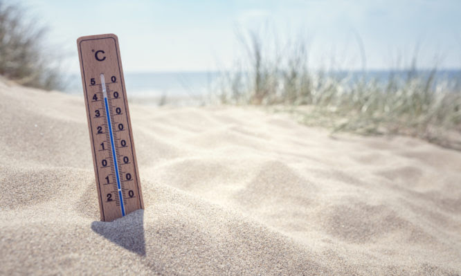 Thermometer on the beach showing high temperature  background