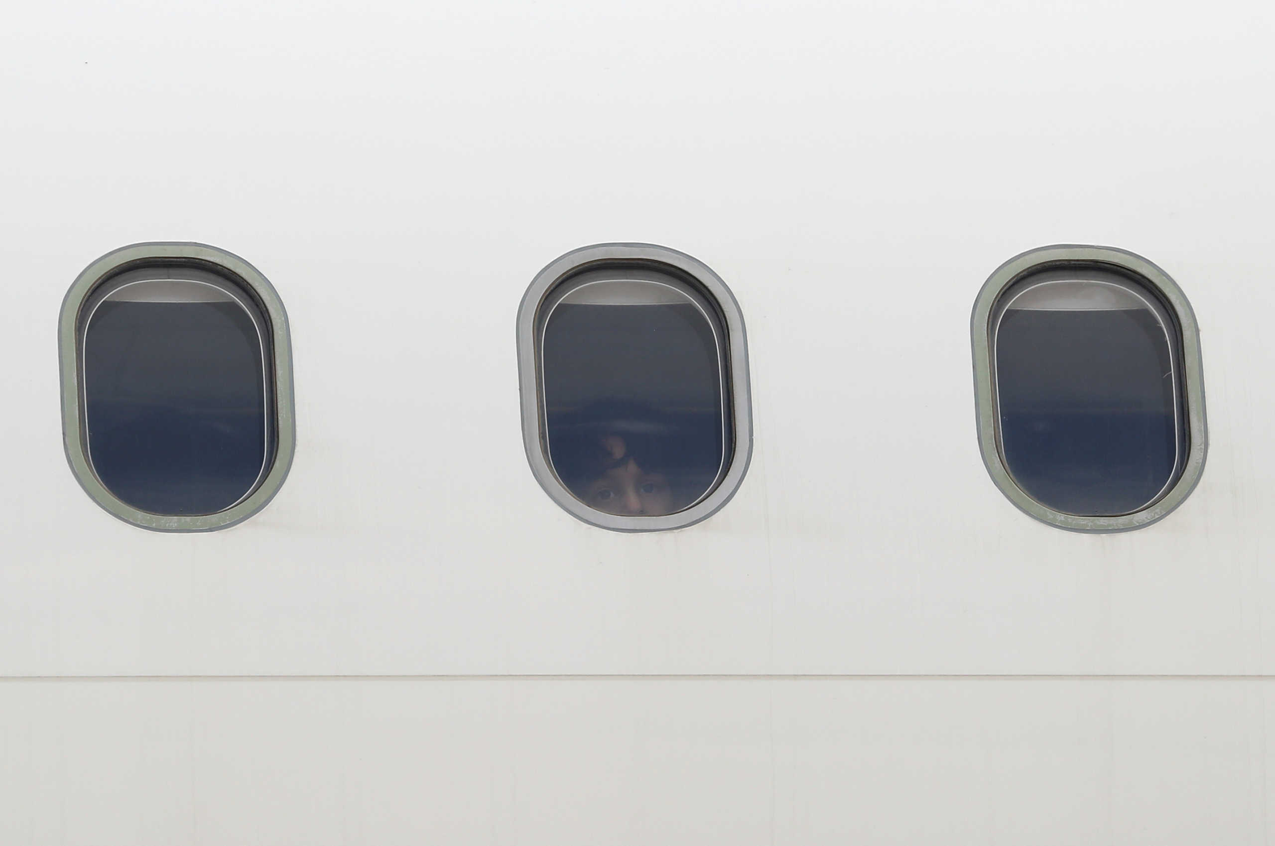 A child looks out of a window as refugees and migrants from overcrowded migrant camps who will be transferred to Britain where they will reunite with their families, during the coronavirus disease (COVID-19) outbreak, board their flight at the Athens International Airport, Greece, May 11, 2020. REUTERS