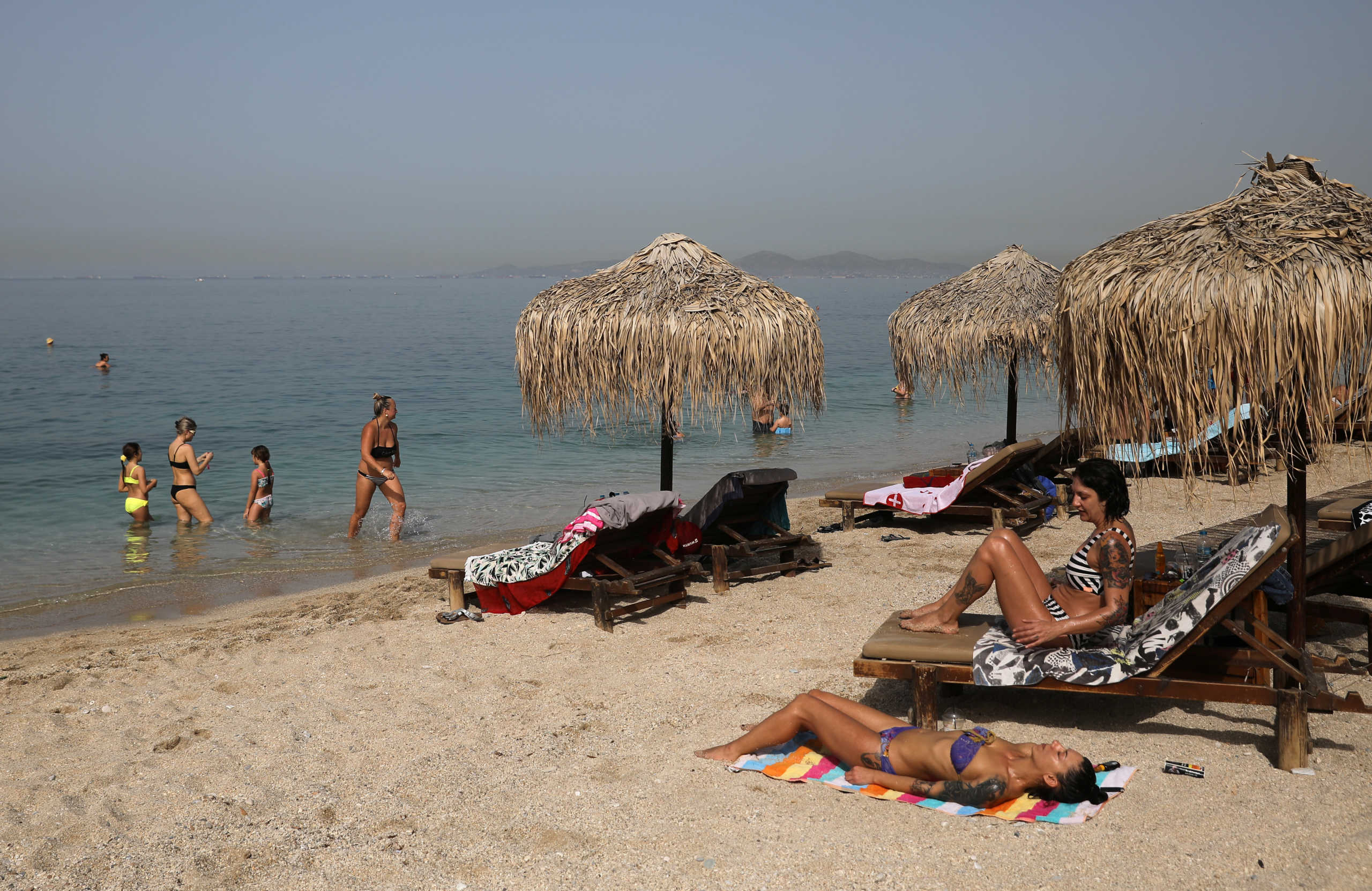 People enjoy the sun during the official reopening of beaches to the public following the easing of measures against the spread of the coronavirus disease (COVID-19), in Athens, Greece, May 16, 2020. REUTERS
