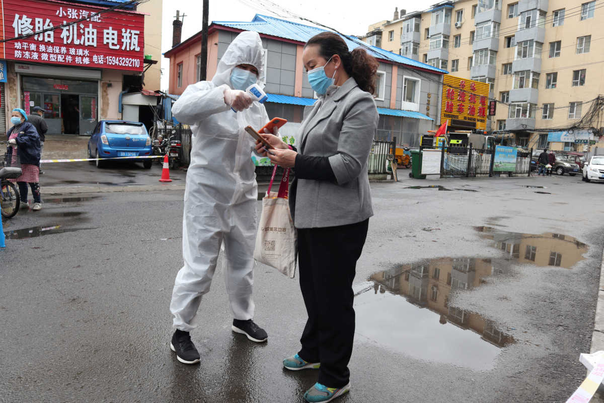 A worker in protective suit takes body temperature measurement of a woman following the coronavirus disease (COVID-19) outbreak in Jilin, Jilin province, China May 17, 2020. Picture taken May 17, 2020. cnsphoto via REUTERS   ATTENTION EDITORS - THIS IMAGE WAS PROVIDED BY A THIRD PARTY. CHINA OUT.
