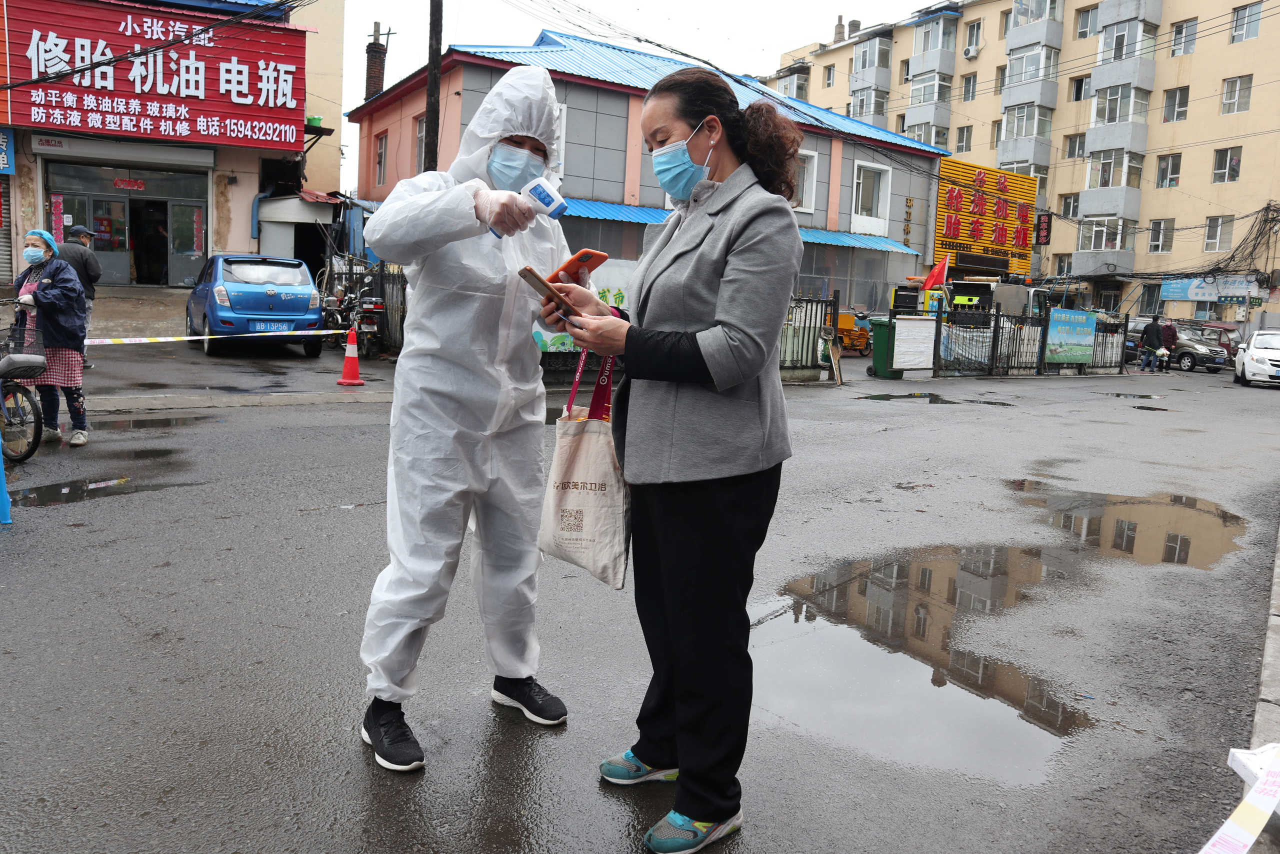 A worker in protective suit takes body temperature measurement of a woman following the coronavirus disease (COVID-19) outbreak in Jilin, Jilin province, China May 17, 2020. Picture taken May 17, 2020. cnsphoto via REUTERS   ATTENTION EDITORS - THIS IMAGE WAS PROVIDED BY A THIRD PARTY. CHINA OUT.