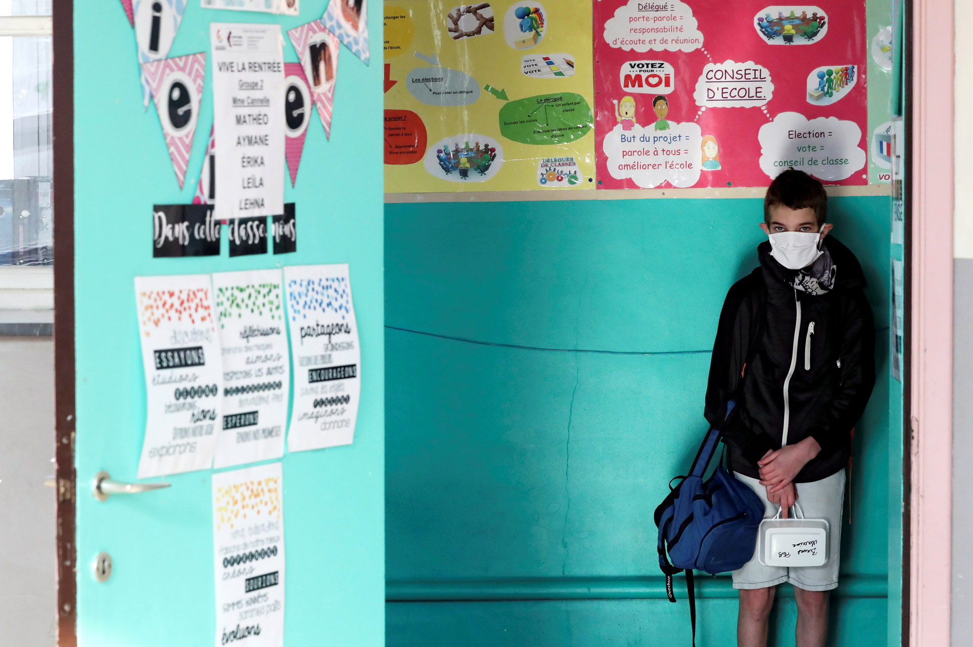 A student wearing a protective face mask stands by a wall at a francophone primary school during its reopening in Jumet, as a small part of Belgian children head back to their schools with new rules and social distancing measures, during the outbreak of the coronavirus disease (COVID-19), in Jumet, Belgium, May 18, 2020. REUTERS