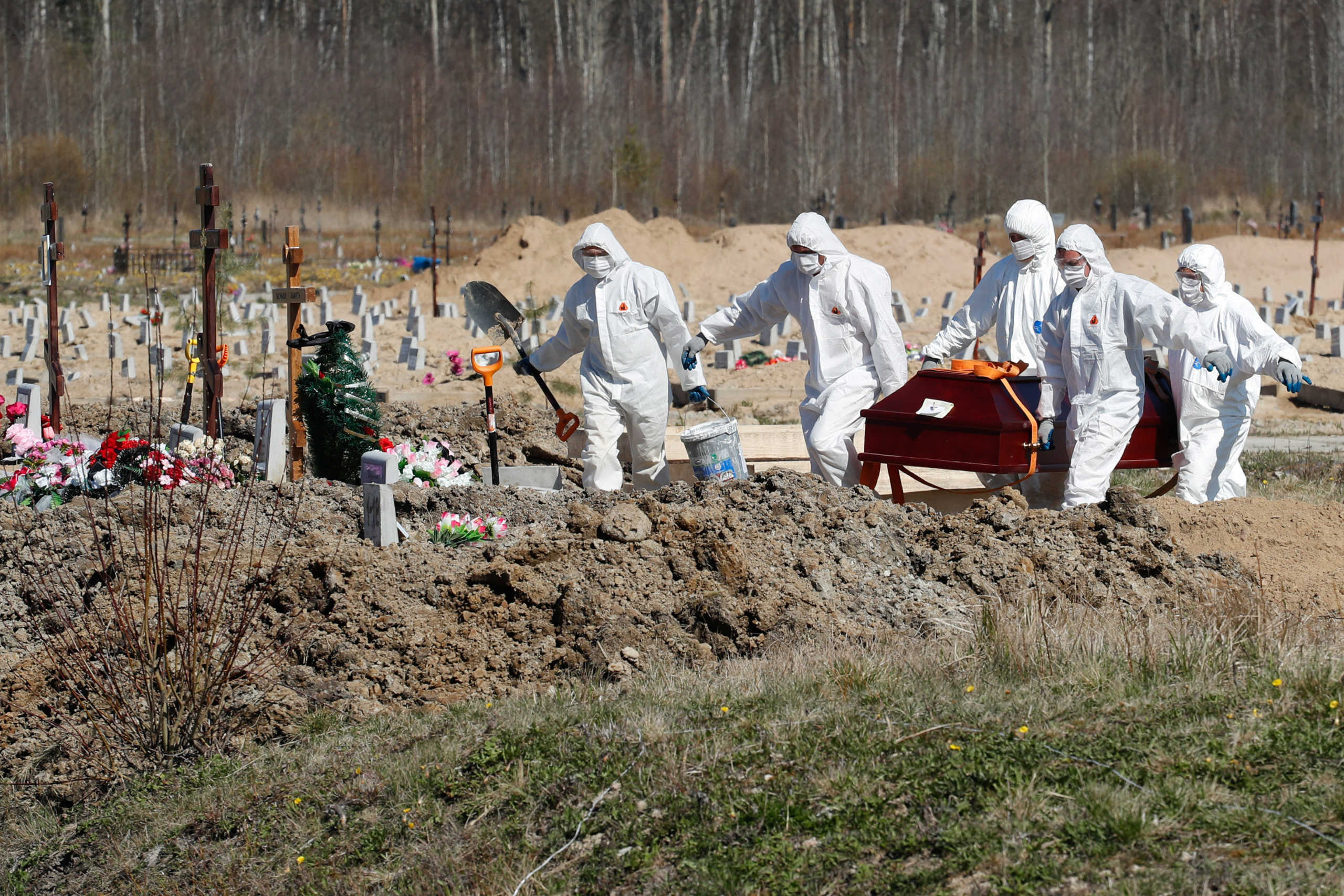 Grave diggers wearing personal protective equipment (PPE) carry a coffin while burying a coronavirus disease (COVID-19) victim in the special purpose section of a graveyard on the outskirts of Saint Petersburg, Russia May 5, 2020. REUTERS