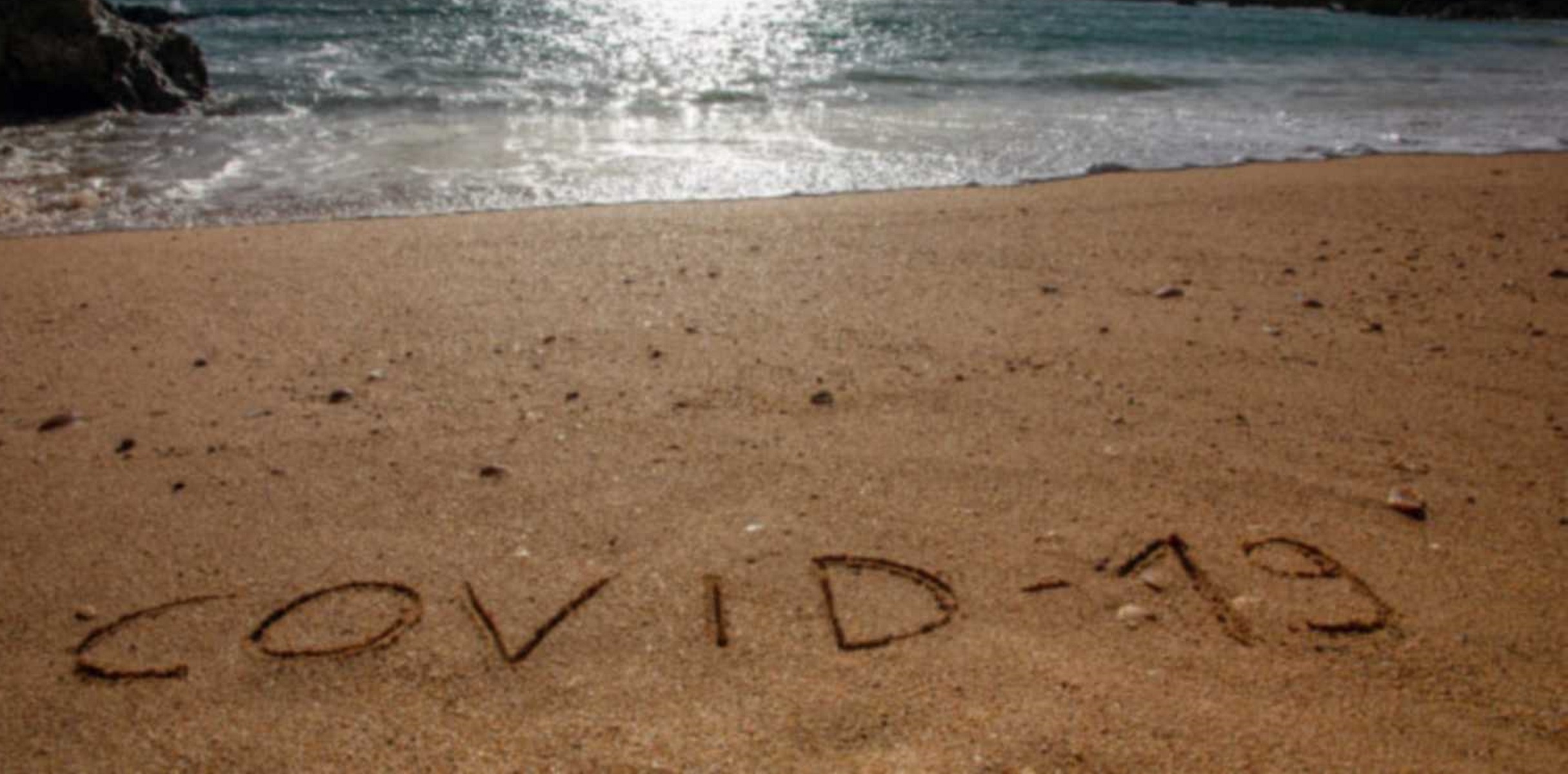Travel and tourism concept for pandemic alert, flights and trips cancellation.  Text written on the sandy beach in Algarve.