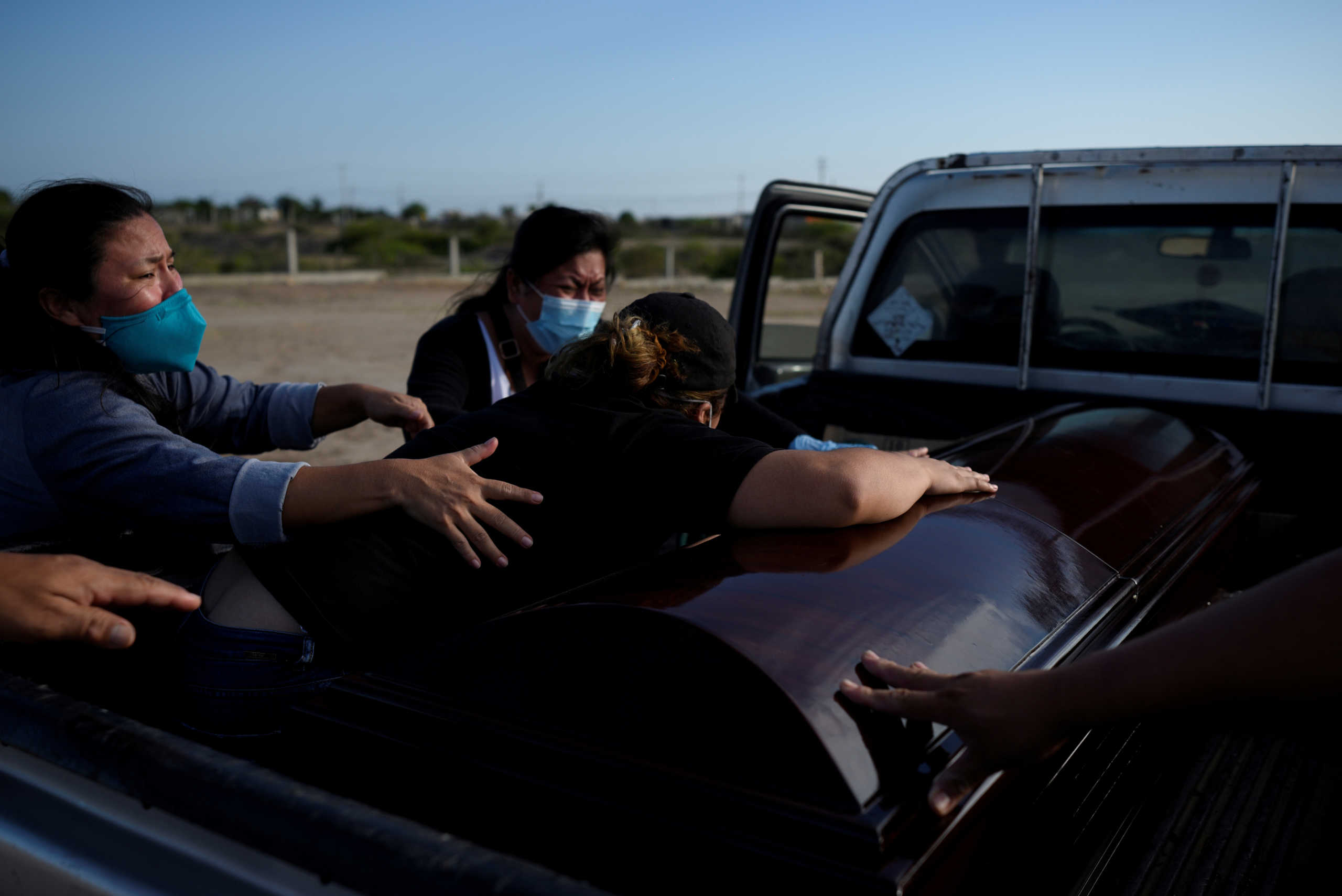 Sulin Sarango, 25, touches her father Angel Sarango's coffin, who died earlier that day after reporting symptoms consistent with COVID-19, as she mourns with her sister's Sandy Sarango and and Betsy Sarango at the cemetery El Cementerio General de Puerto Chanduy, during the coronavirus disease (COVID-19) outbreak, in Chanduy, Ecuador, May 1, 2020. REUTERS