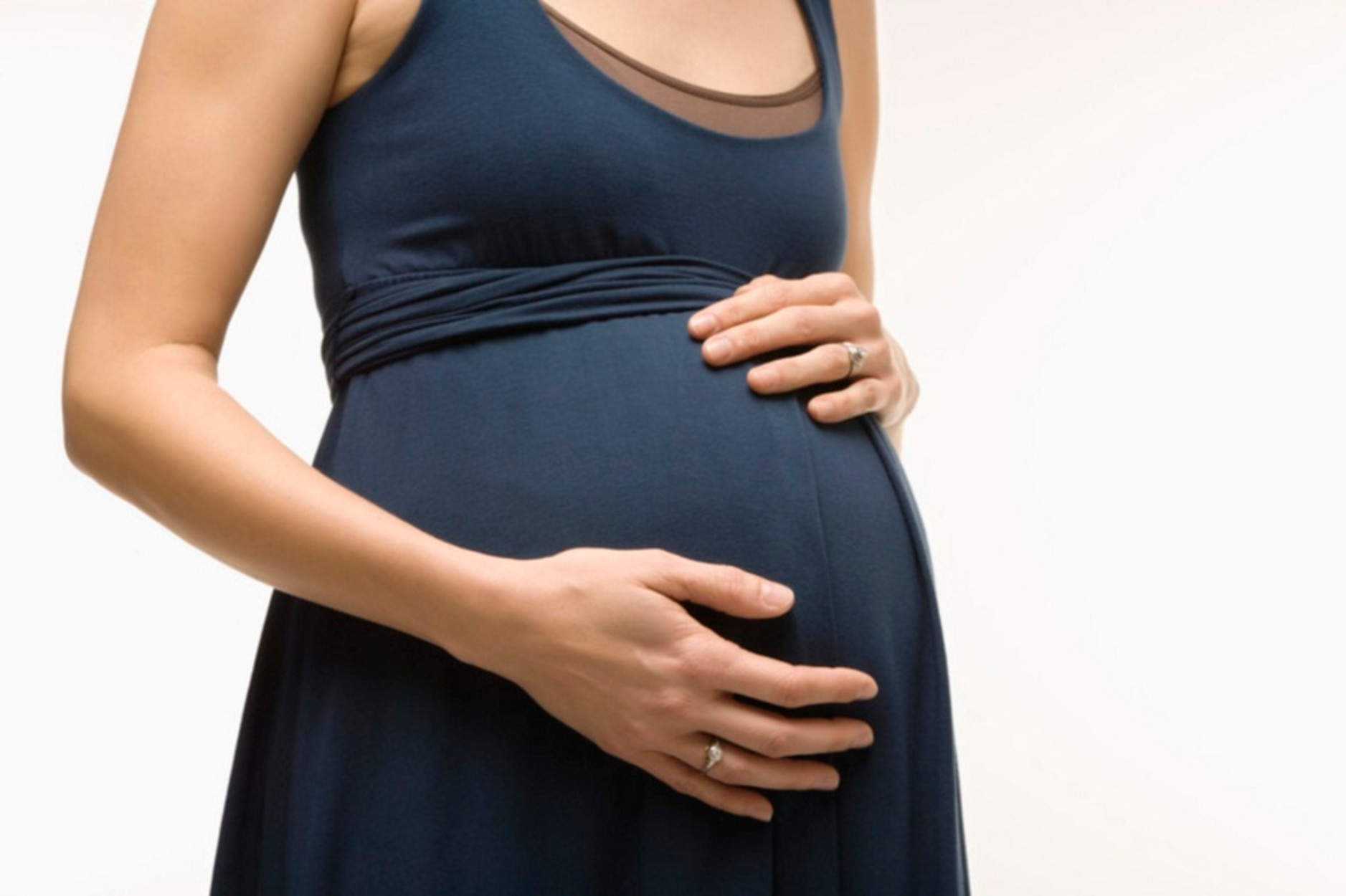 Caucasion mid-adult pregnant woman with hands on belly.