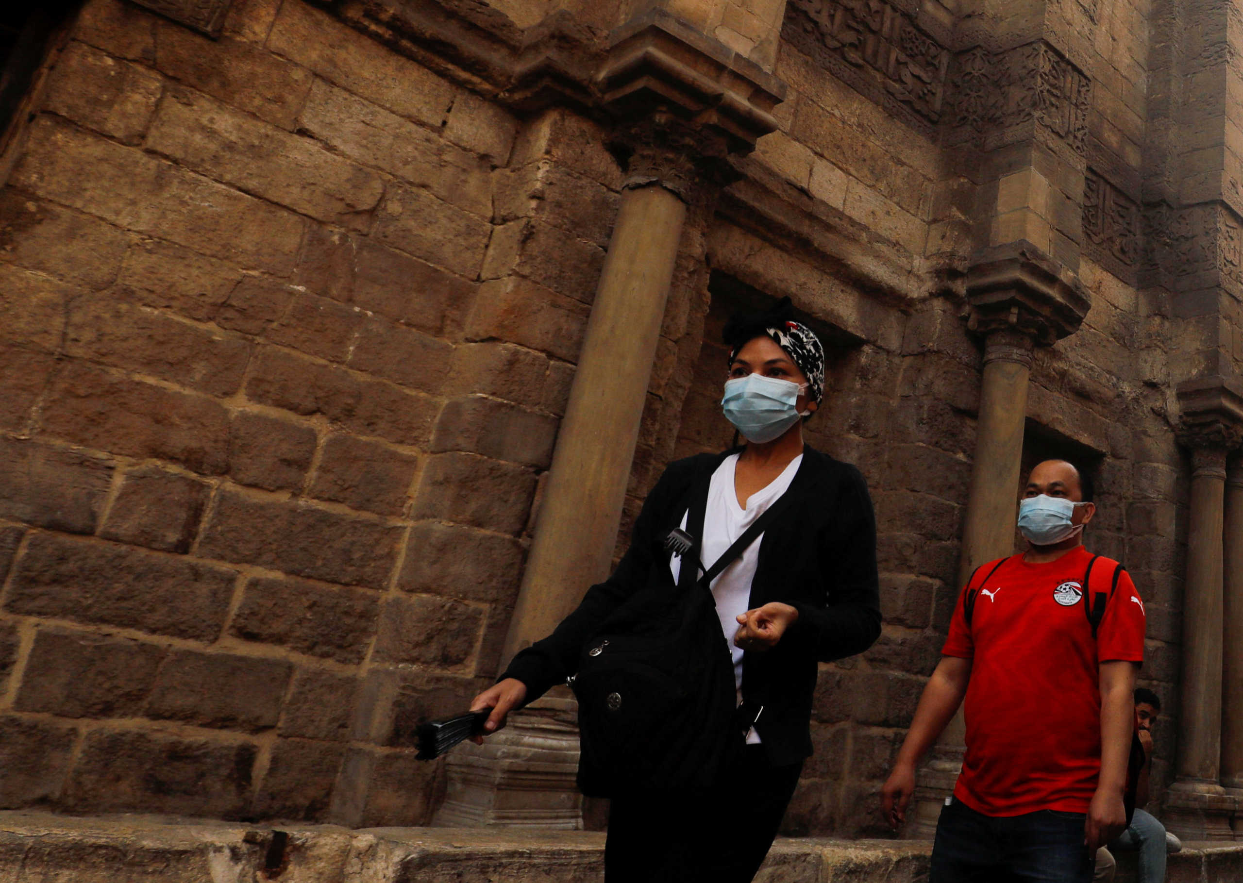Tourists wearing protective face masks, amid concerns over the coronavirus disease (COVID-19), walk in front of closed mosques and Islamic schools at El Moez Street in old Islamic Cairo, Egypt April 30, 2020. REUTERS