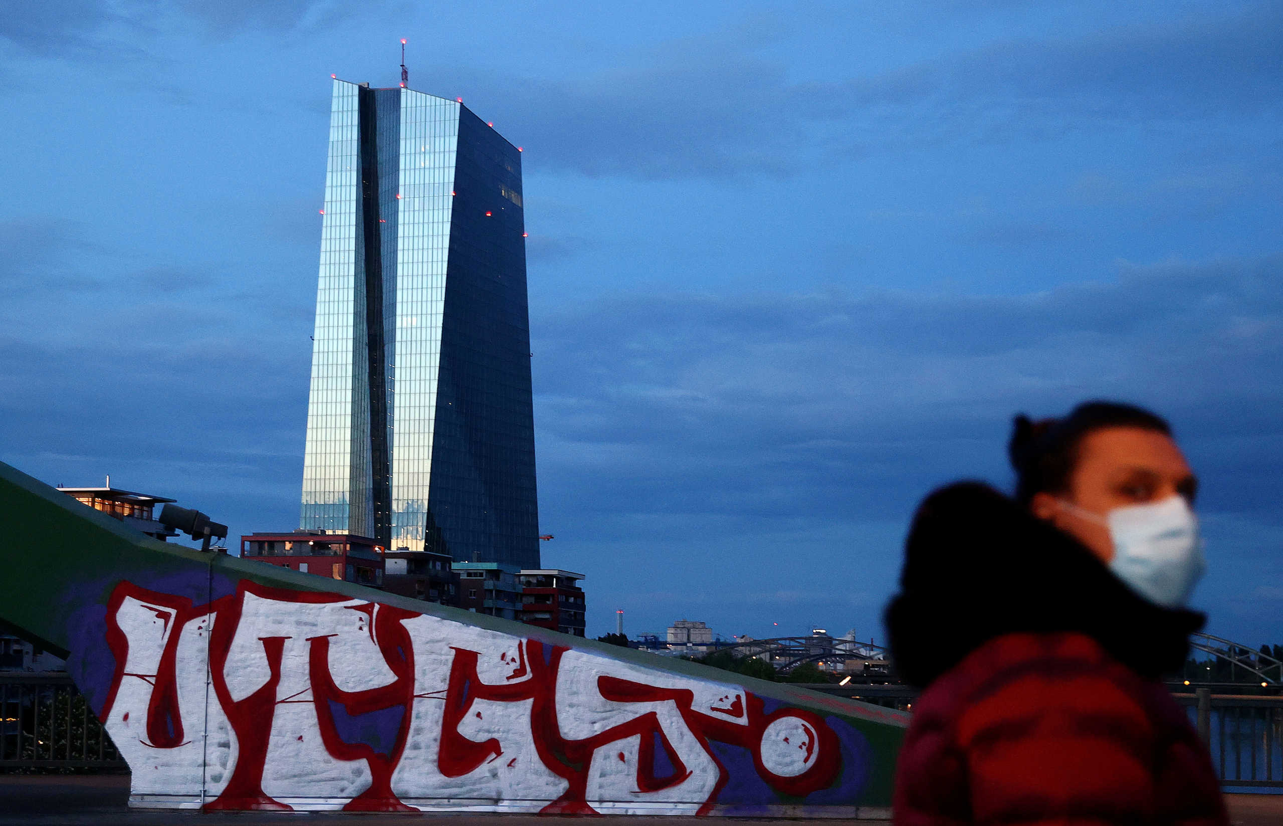 FILE PHOTO: A woman, wearing a protective mask walks past the head quarter of the European Central Bank (ECB) during sunset in Frankfurt, Germany, April 29, 2020, as the spread of the coronavirus disease (COVID-19) continues.   REUTERS