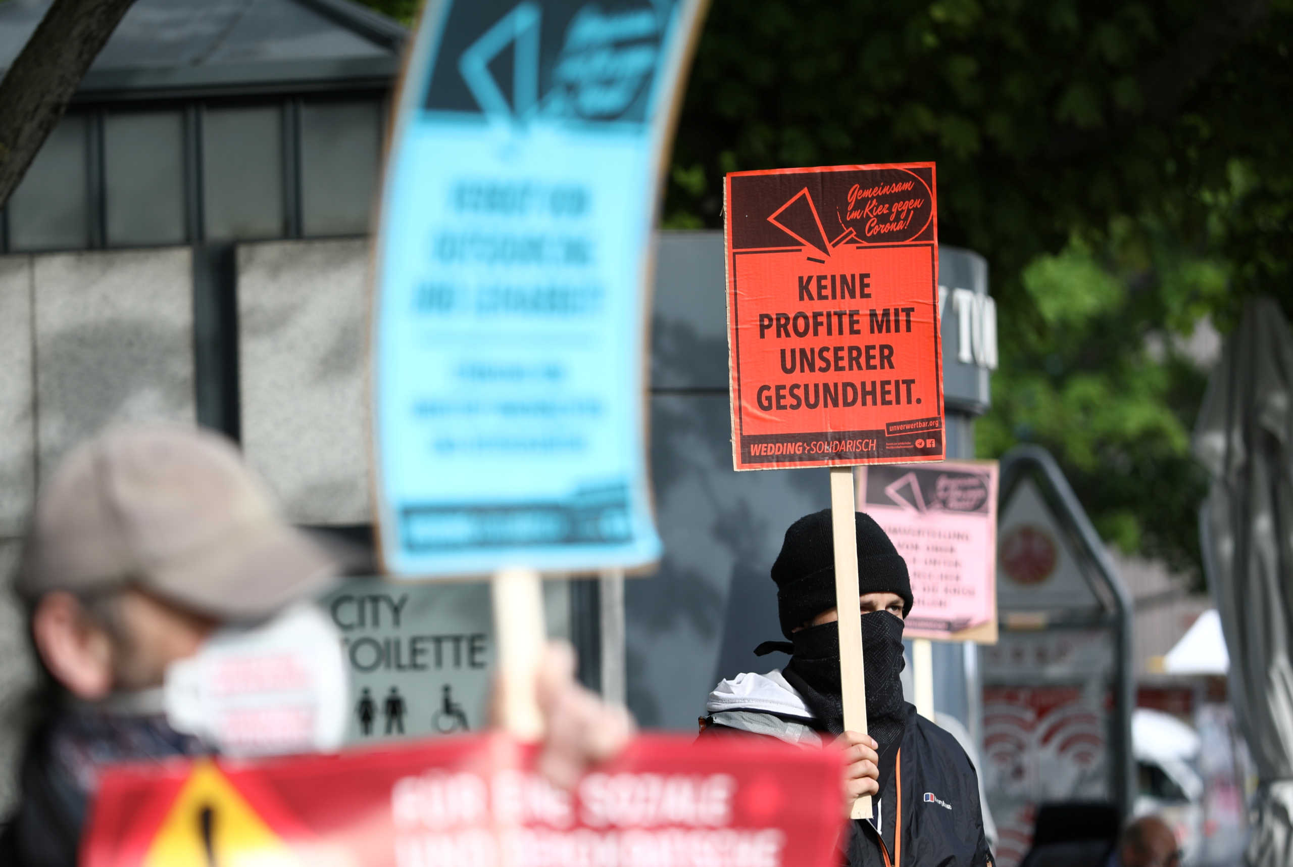 A man holds a placard reading "No profits with our health" as he attends a left wing protest ahead the vigil of May Day demonstrations, during the coronavirus disease (COVID-19) outbreak, in Berlin, Germany, April 30, 2020. REUTERS
