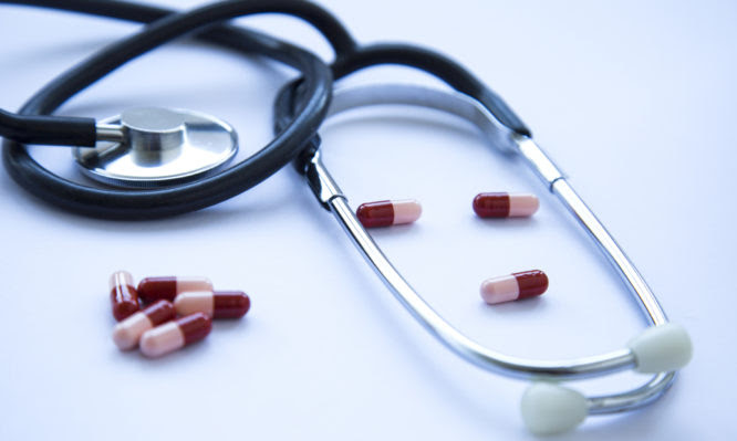 Metal stethoscope for doctor diagnosis and medical drug pill.Horizontal composition, studio shot.