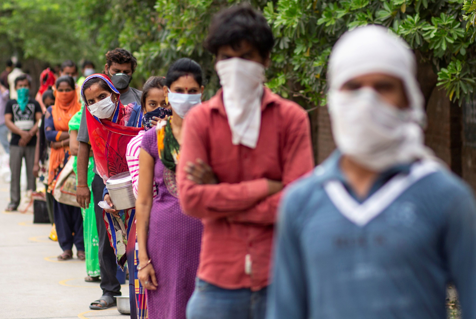 FILE PHOTO: People wait to receive free food at an industrial area, during an extended nationwide lockdown to slow the spreading of the coronavirus disease (COVID-19) in New Delhi, India, April 23, 2020. REUTERS