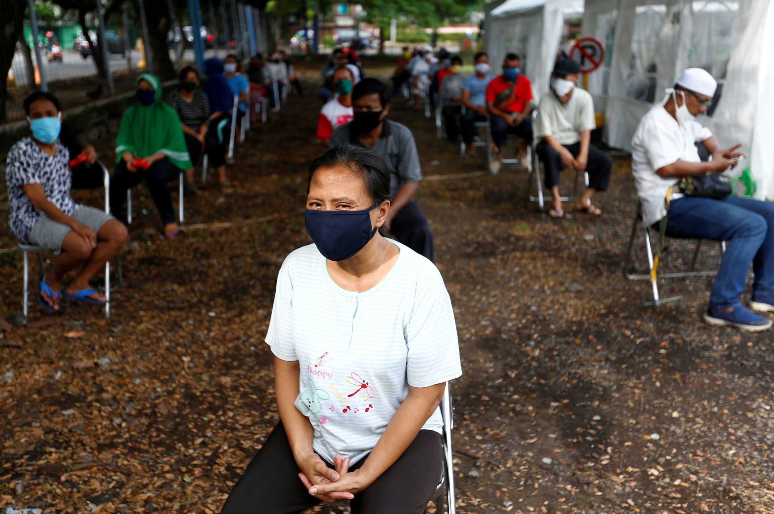 FILE PHOTO: People wearing protective face mask practice social distancing while receiving rice from an automated rice ATM distributor amid the coronavirus disease (COVID-19) spread in Jakarta, Indonesia May 4, 2020. REUTERS