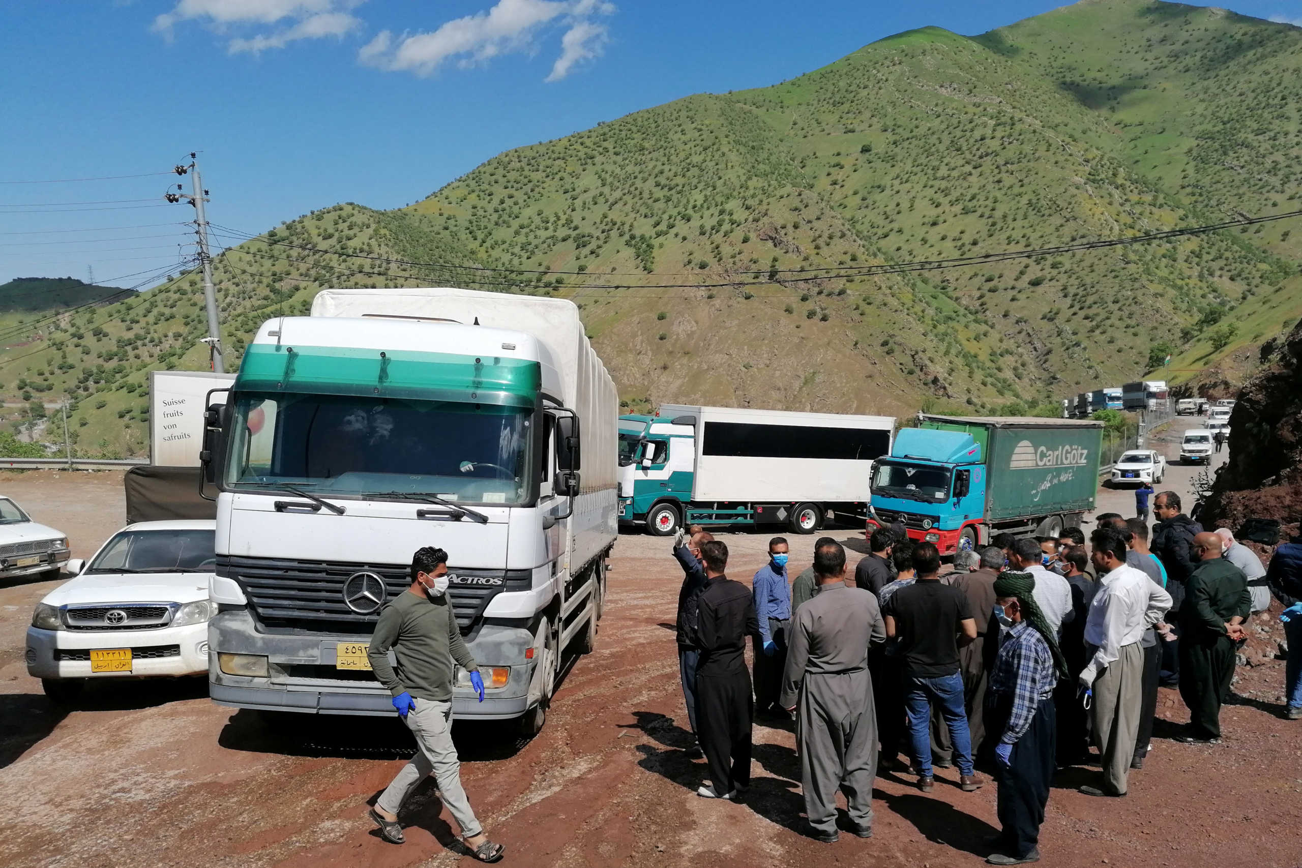 People gather near trucks after the border between Iraqi Kurdistan and Iran partially reopened for the first time since the outbreak of the coronavirus disease (COVID-19), at the border between Iran and Iraqi Kurdistan in Halabja Province, Iraq May 3, 2020. REUTERS