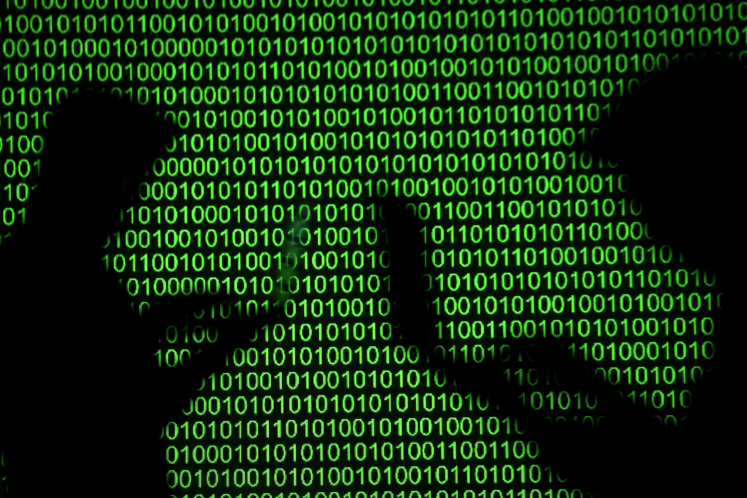 Silhouettes of laptop users are seen next to a screen projection of binary code are seen in this picture illustration taken March 28, 2018.  REUTERS