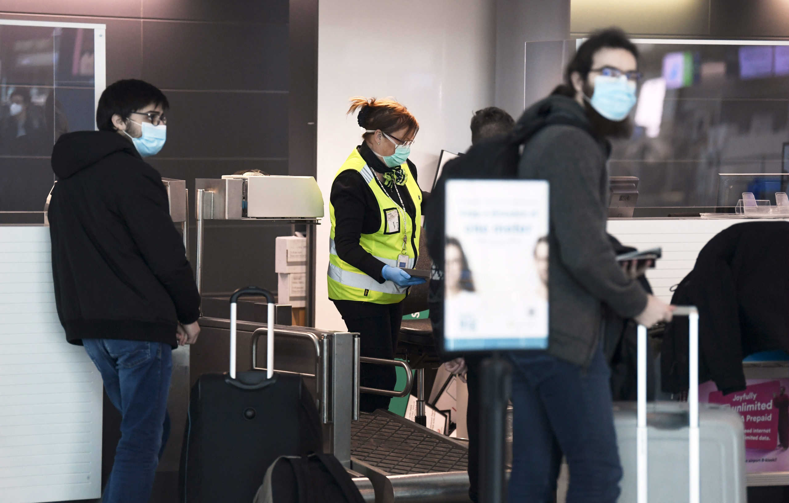 An employee wearing a protective face mask and gloves serves passengers at the customer service of the Helsinki International Airport in Vantaa, Finland May 13, 2020.   Lehtikuva