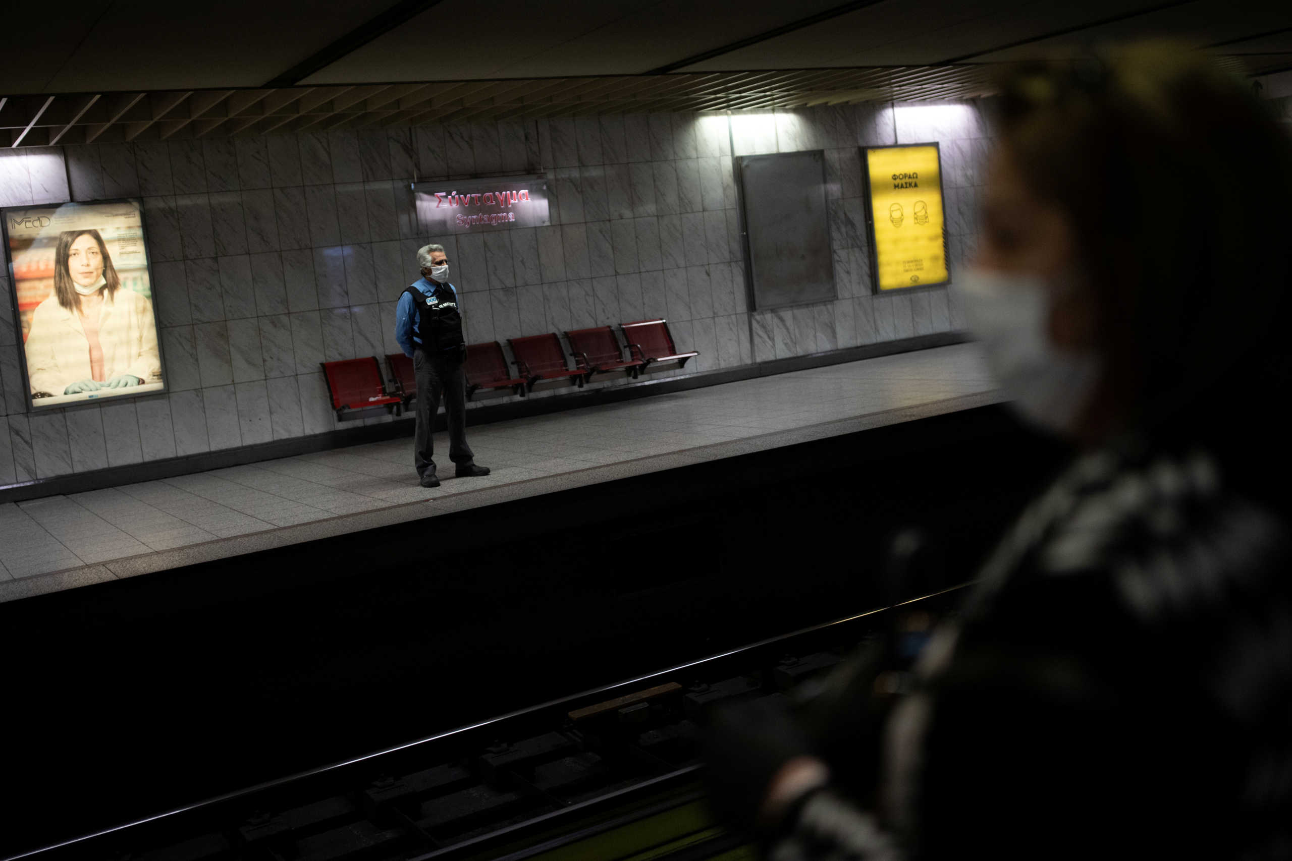 A private security employee stands guard as a commuter wearing a protective face mask waits for a train, at the metro station on Syntagma square, on the first day of easing of a nationwide lockdown against the spread of coronavirus disease (COVID-19), in Athens, Greece, May 4, 2020. REUTERS