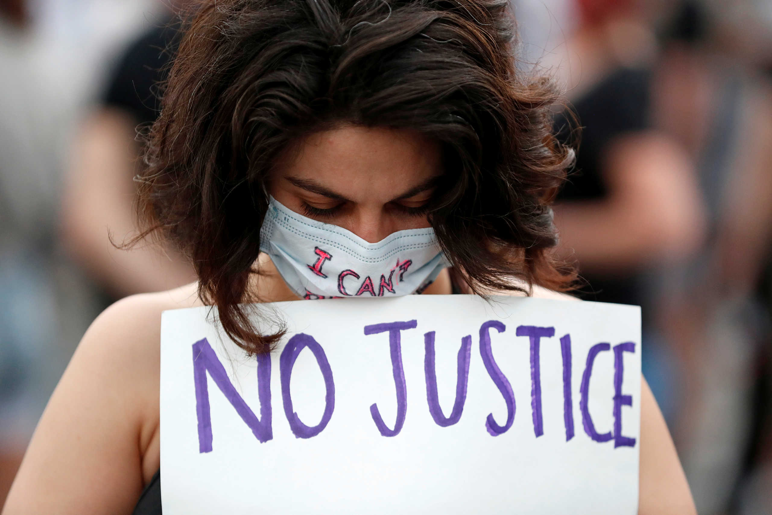 A protester holds a sign at the scene where George Floyd, an unarmed black man, was pinned down by a police officer kneeling on his neck before later dying in hospital in Minneapolis, Minnesota, U.S. May 26, 2020. REUTERS