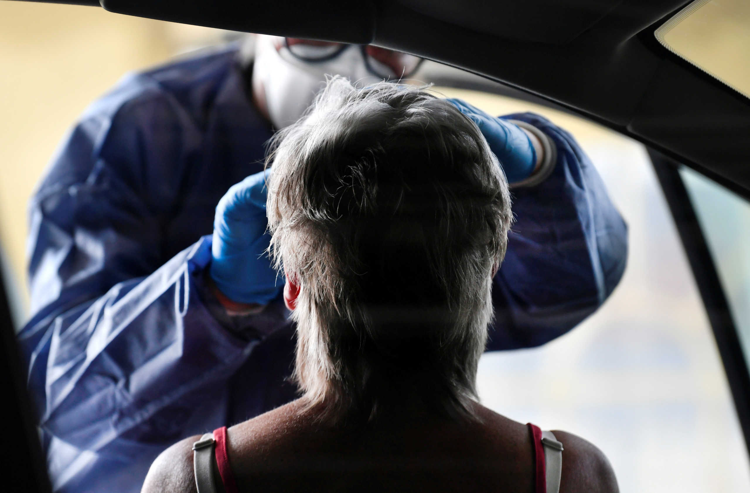A member of medical staff takes coronavirus test samples of a woman during drive-thru coronavirus disease (COVID-19) testing, on a converted ice rink, in Alkmaar, Netherlands April 8, 2020.  REUTERS