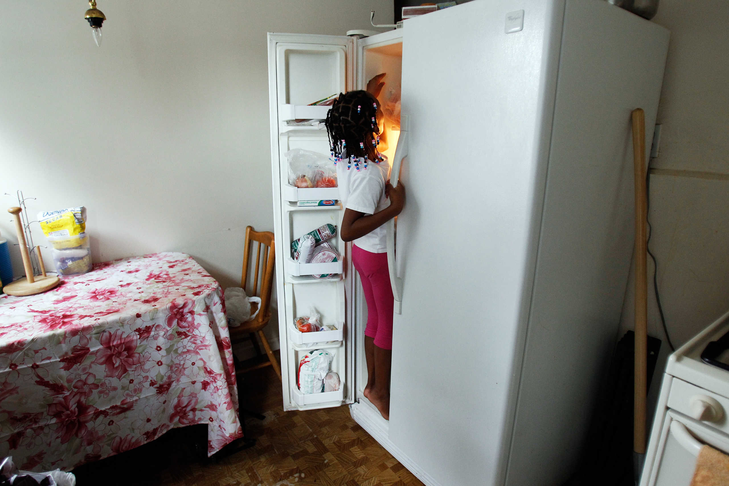 Tashawna Green's daughter Taishaun, 6, reaches into the freezer for an ice pop at her home in Queens Village, New York August 21, 2011. Green who up until recently worked 25 hours a week at Target, is on food stamps and says a good number of her colleagues are too. Green made $8.08 cents an hour working for Target. "It's a good thing that the government helps, but if employers paid enough and gave enough hours, then we wouldn't need to be on food stamps." Picture taken August 21, 2011. To match Insight USA-POVERTY-FOODSTAMPS
