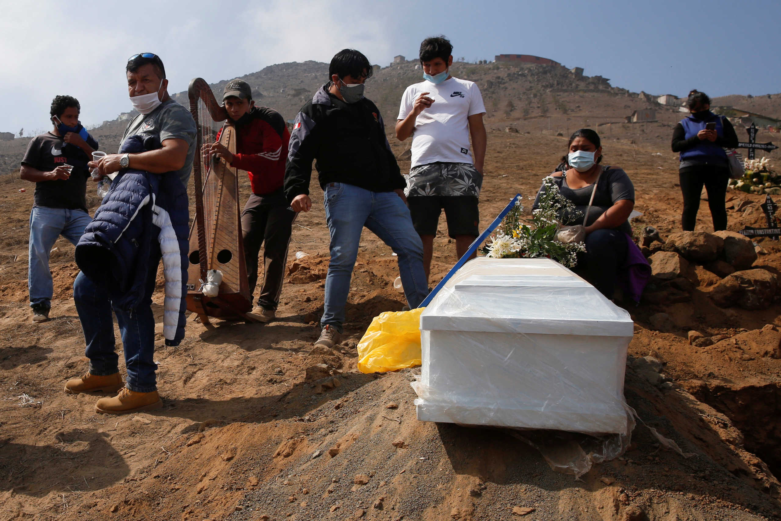 Relatives react next to a coffin containing the body of their loved one, who died of the coronavirus disease (COVID-19), at the Nueva Esperanza cemetery in Lima, Peru, May 27, 2020. REUTERS